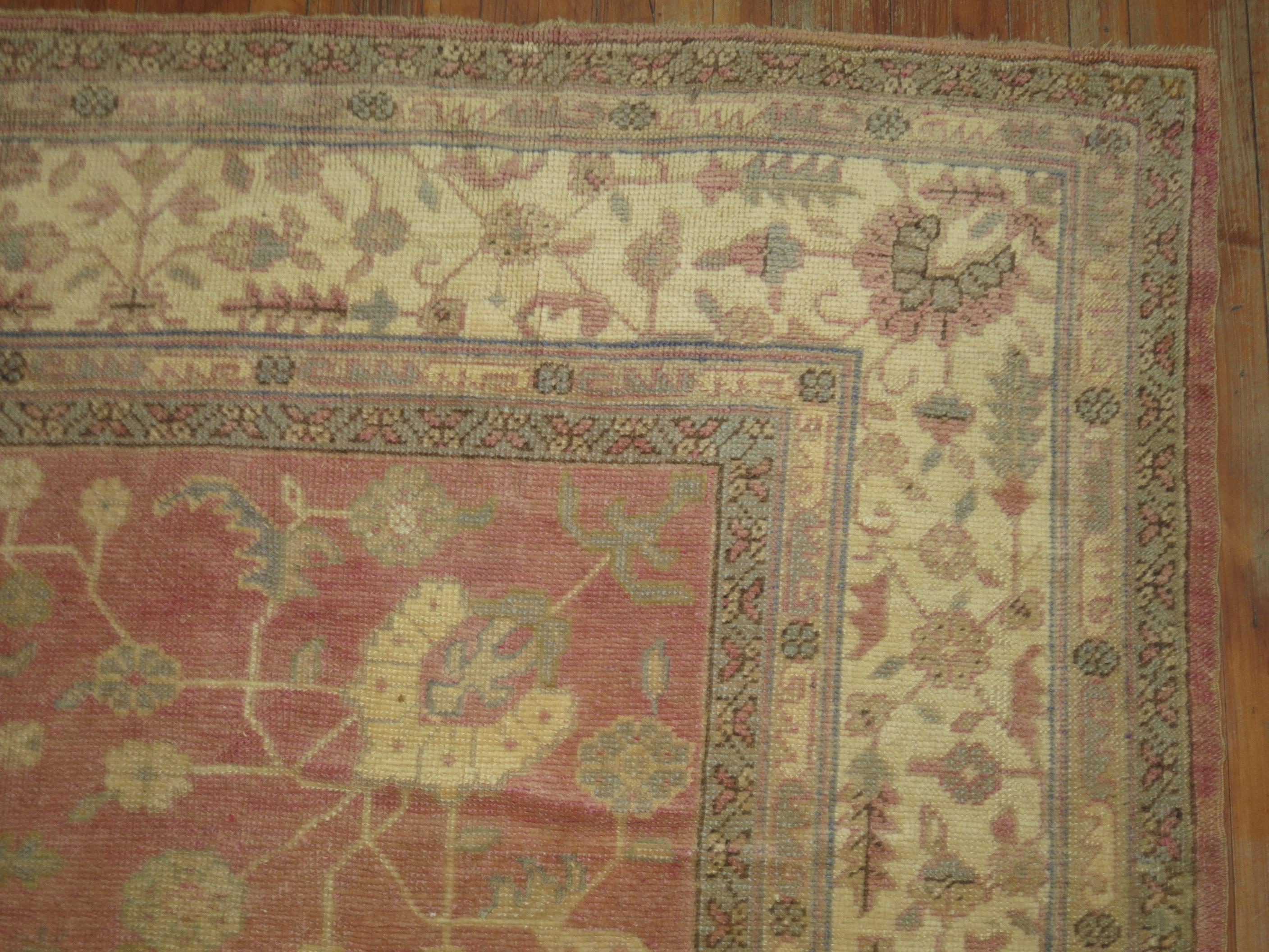 A square shaped antique Turkish Oushak with accents of mint and cream on a salmon colored field.