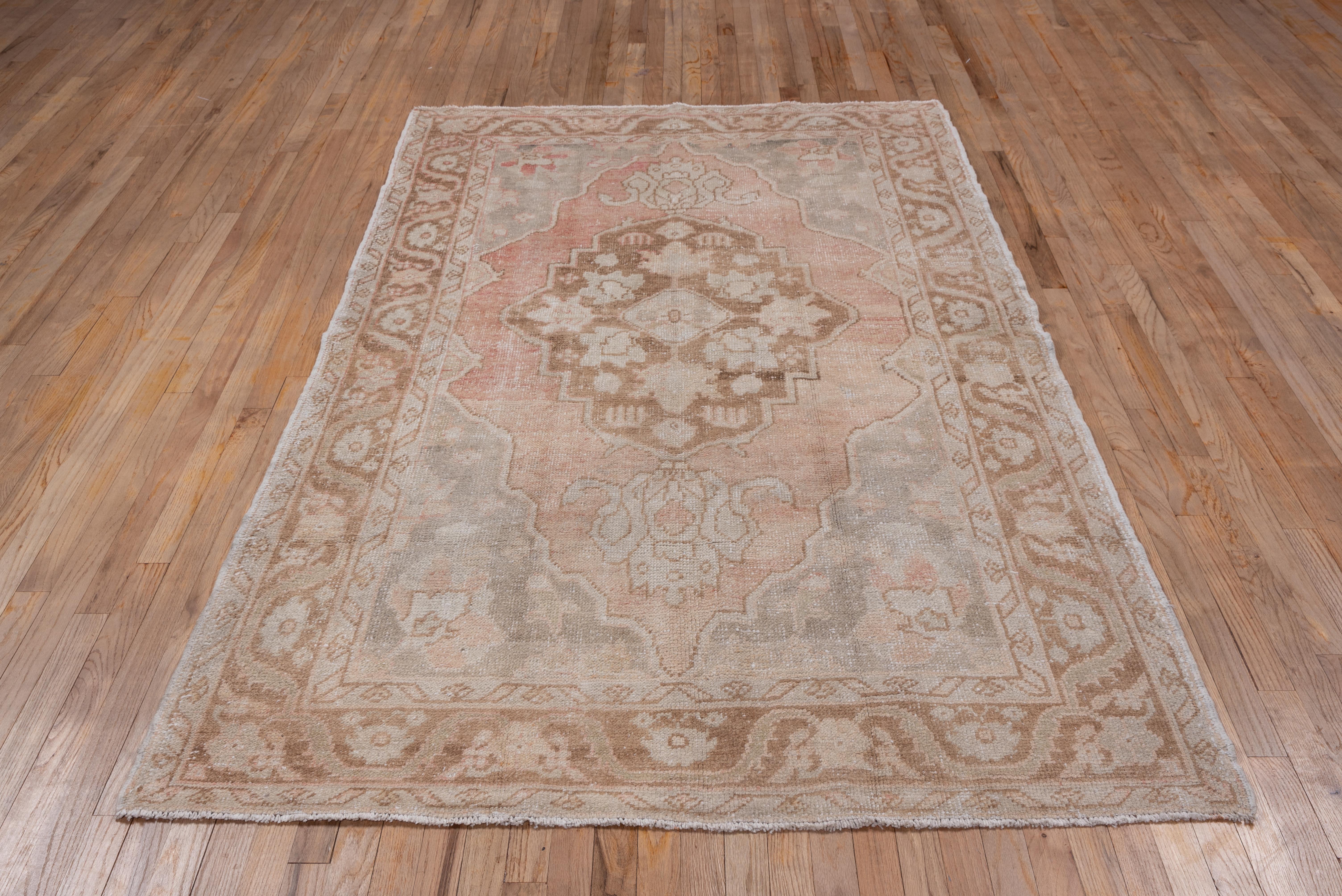 In the Persian Heriz style, the pendanted brown medallion is set on the pale buff sub- field within pearl grey corners. The light brown border displays palmettes joined by a recurving leaf pattern. Slight medallion offset toward one end.