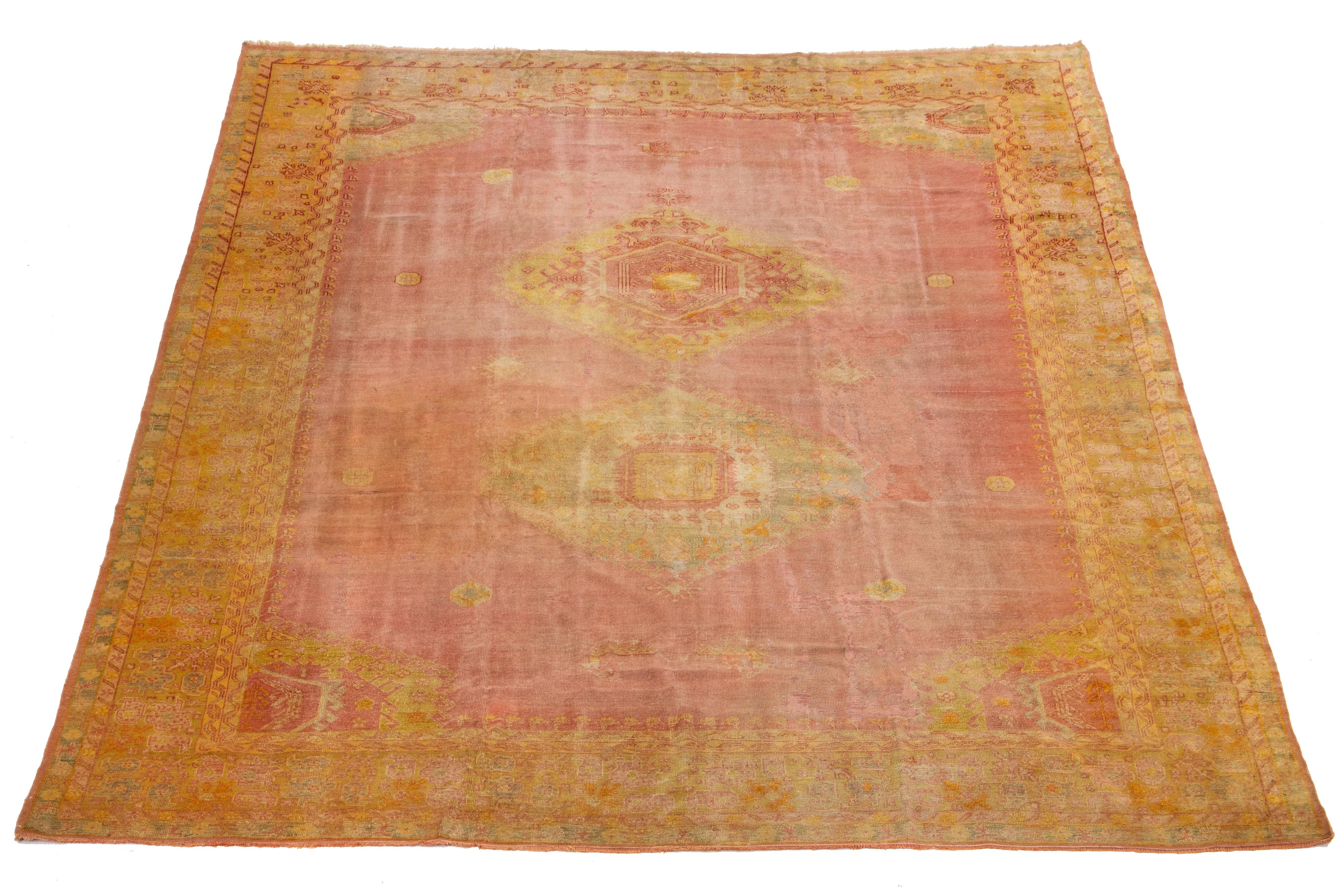 Dieser antike türkische Oushak-Teppich ist ein Unikat, das aus hochwertiger Wolle handgeknüpft wurde. Das auffällige terrakottafarbene Farbfeld und das filigrane Medaillonmotiv mit gelben und beigen Akzenten machen es zu einem echten
