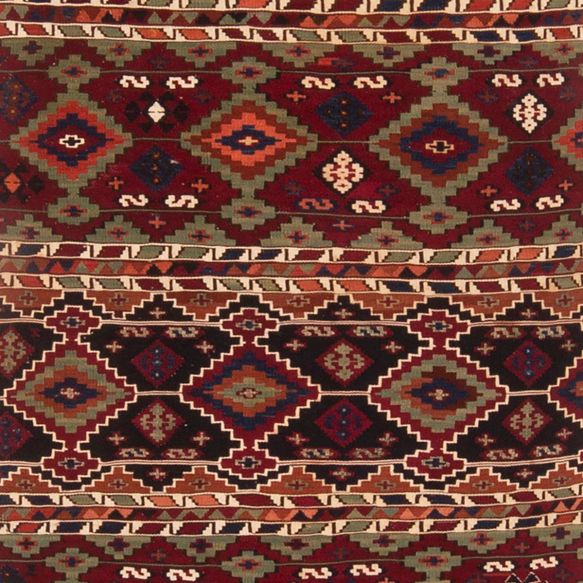 Originating from Turkey between 1900-1920, this antique geometric wool Kilim rug features a distinct combination of both iconic and seldom-seen Turkish symbols. flat-woven in high quality wool, the alternating rows of burgundy red and navy blue with