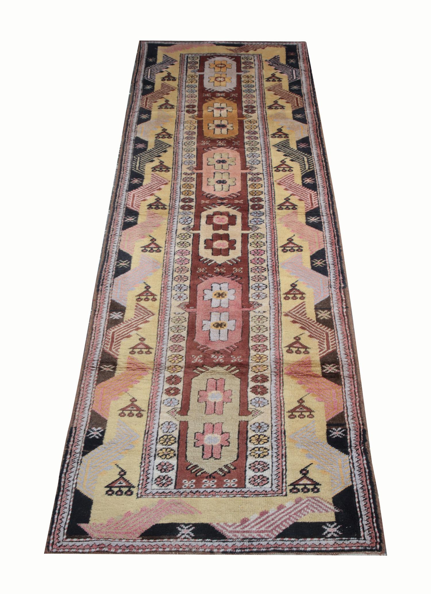 This antique Milas carpet runner has a multi-medallion design with earthy hues of brown, gold and rust red and a rich palette of colours. Featuring geometric rug design similar to those of Caucasian provenance combined with floral rug motifs inside