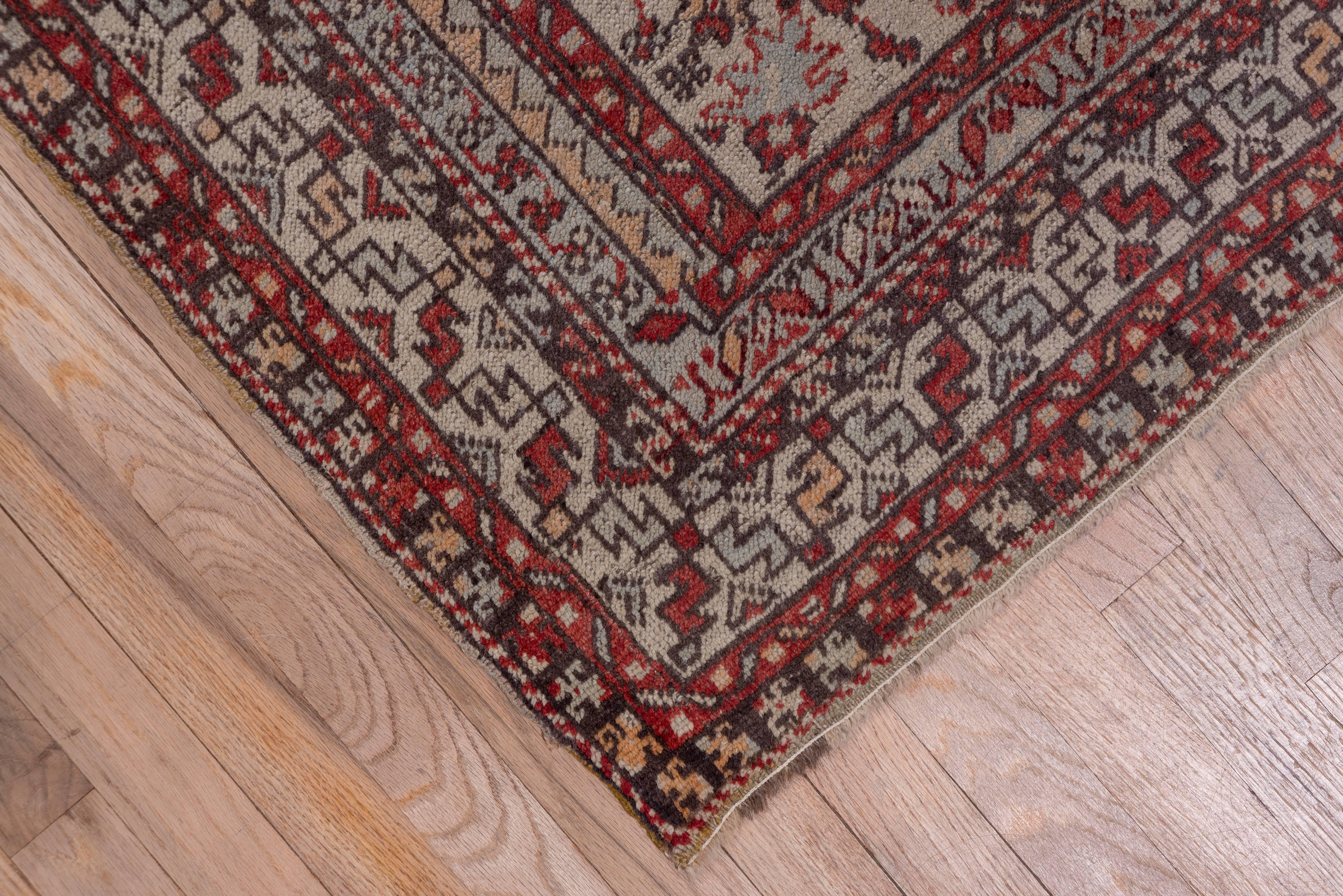 The field of this eastern Turkish runner is divided into three parts. Brown with a red medallion; One panel is red with gray and another is gray with tan. The ivory main border has a pattern of short, serrated diagonal leaves.