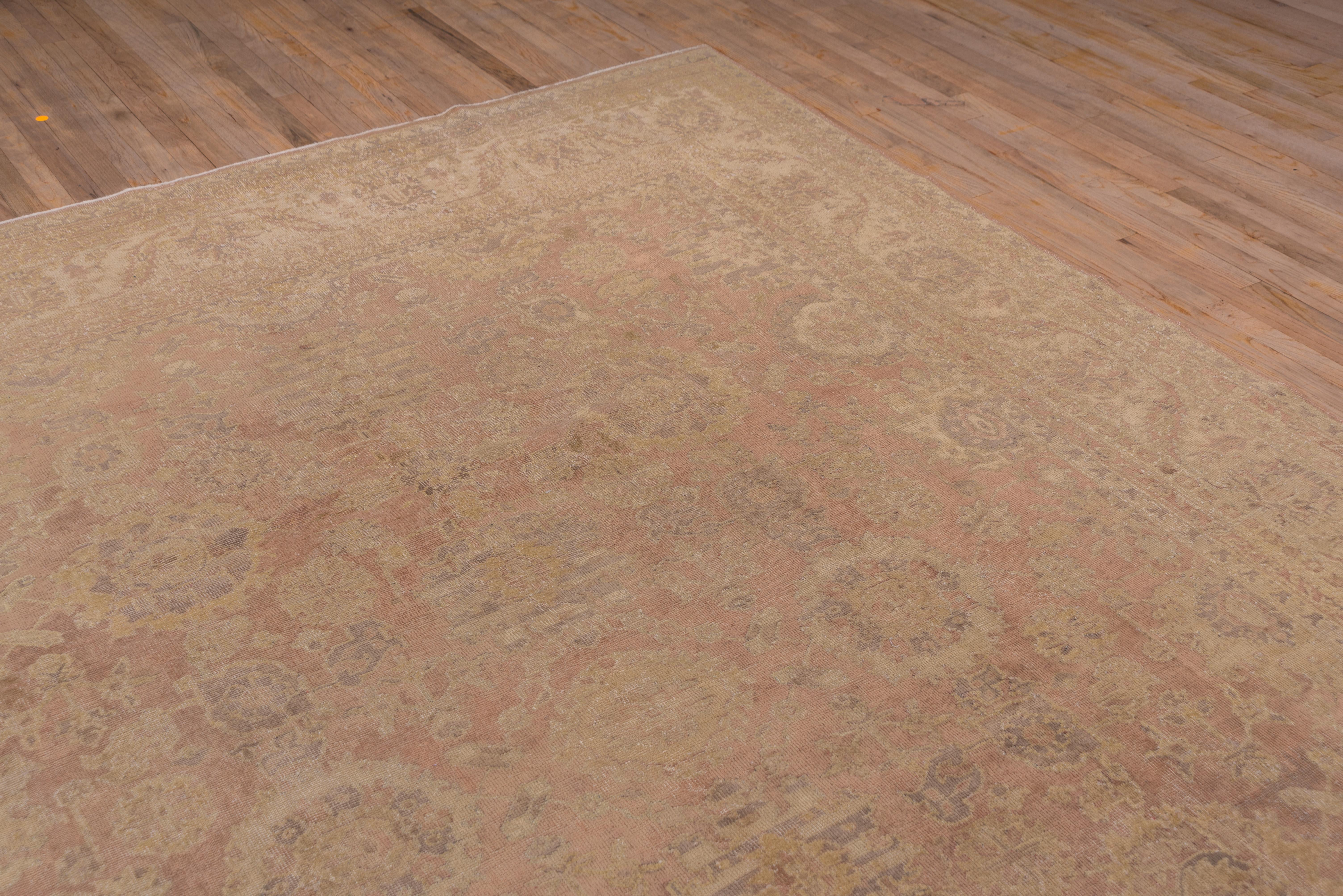 Thisd east Turkish city carpet displays a yellow on soft pink pattern of ragged rosettes, abstract flowers and flame palmettes in a quasi-Harshang style, with a light pink field, and cream outlines and accents. Medium weave.