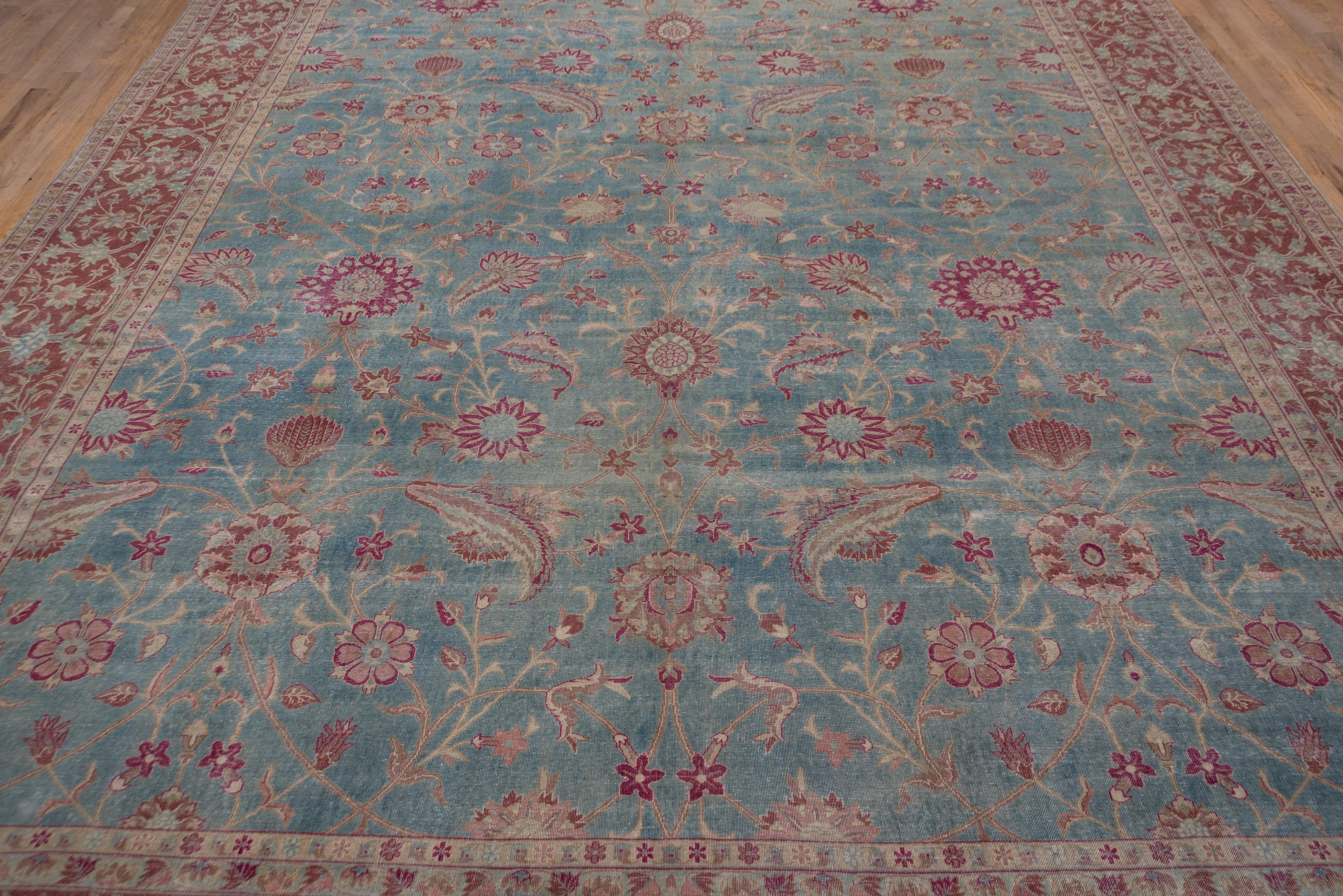 The light blue ground shows a spacious rising palmette allover pattern with large, barbed sickle leaves passing over rosettes in a quasi-three dimensional style. Red border with almost closed elliptical scrolls around rosettes. Cotton foundation.