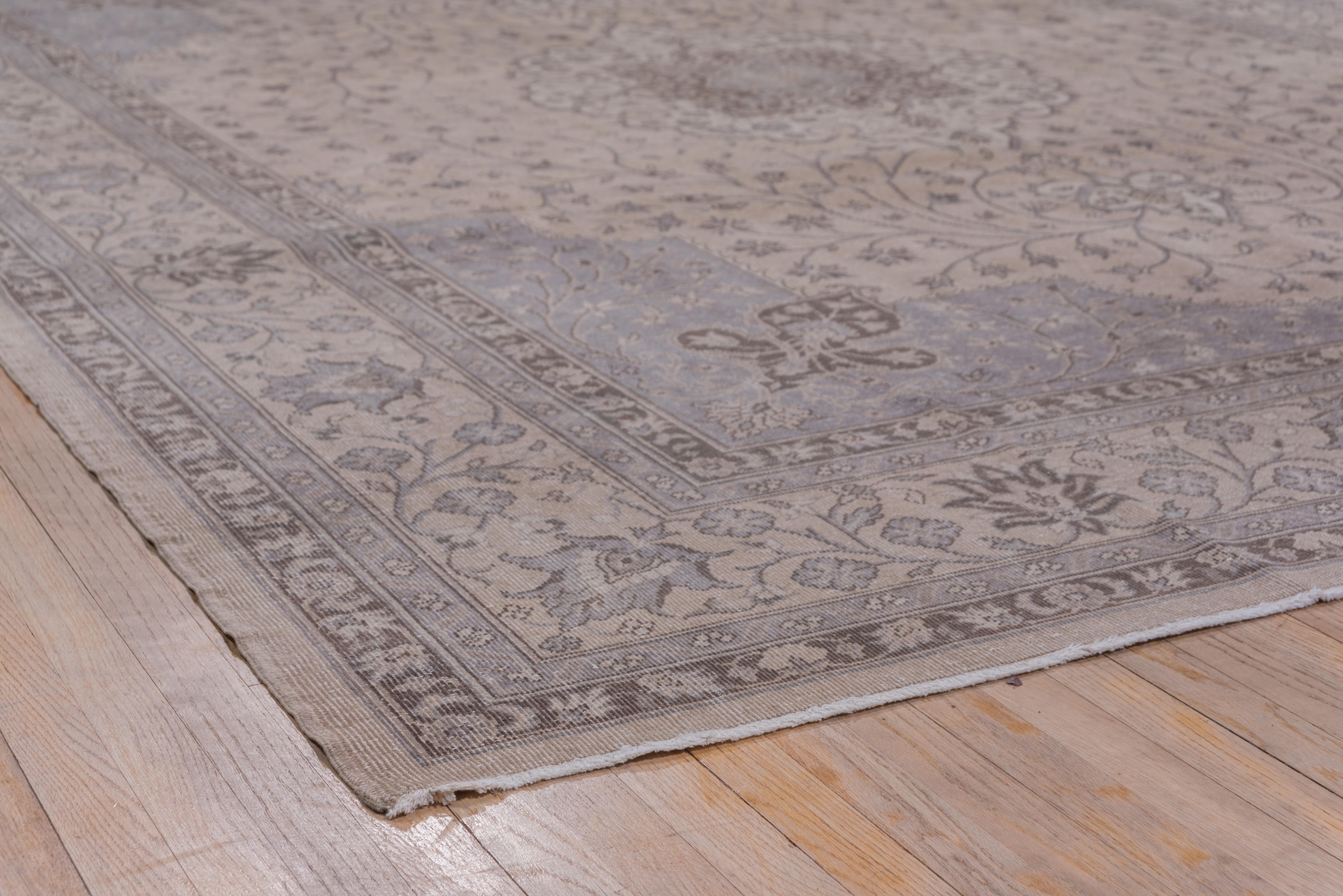 In the Tabriz manner, with a light brown and taupe field centered by a lightly scalloped ecru medallion, and an inner actograms Sub-medallion and elegantly flowing floriated stems. Blue gray extended corners. Main border of finely drawn reversing
