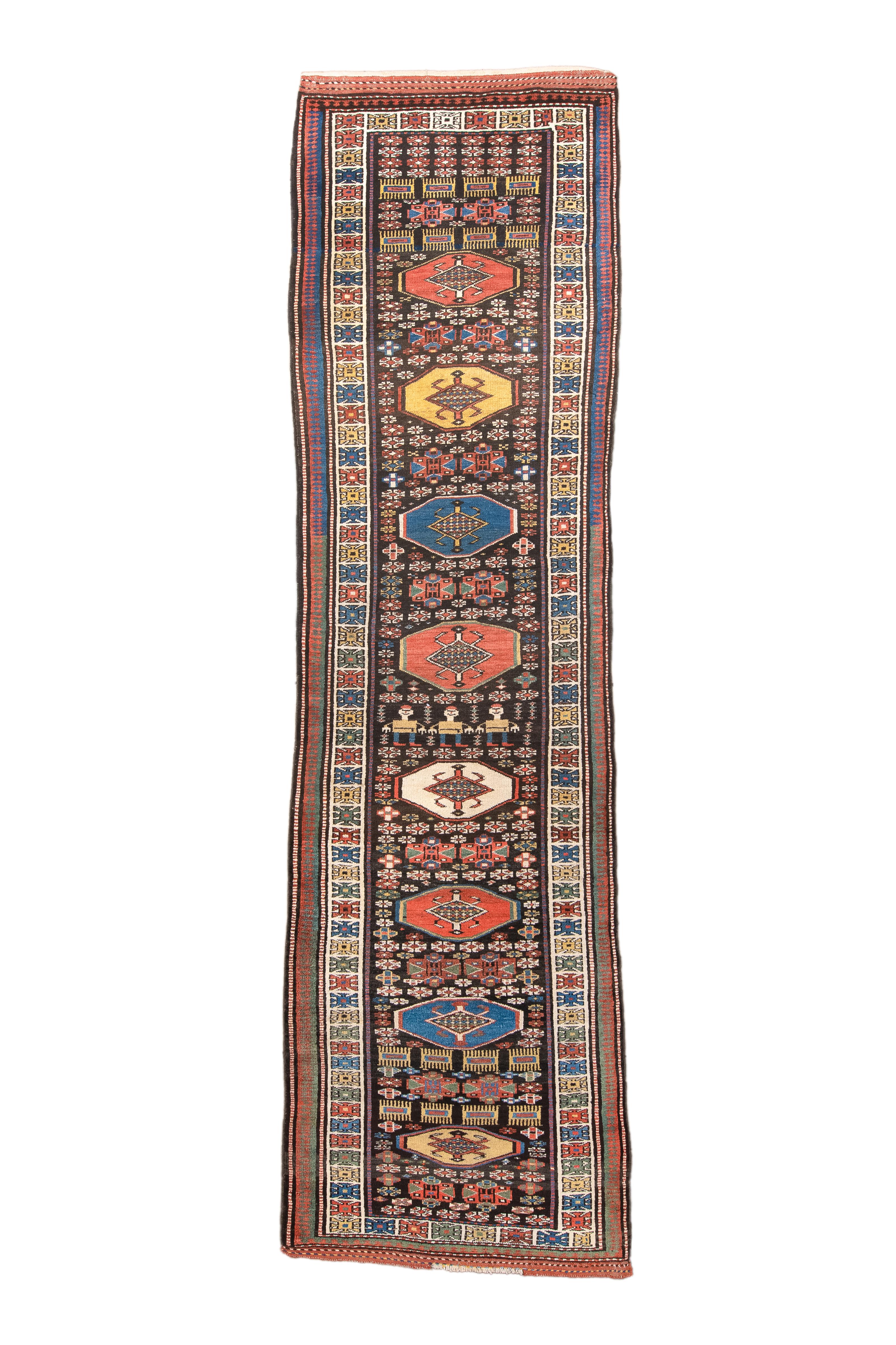 Parti per un viaggio incantevole attraverso il ricco arazzo delle tribù curde con questo straordinario tappeto runner curdo ornato dall'intramontabile disegno Medallion del 1910. L'accattivante miscela di tonalità Cola e White trasforma qualsiasi