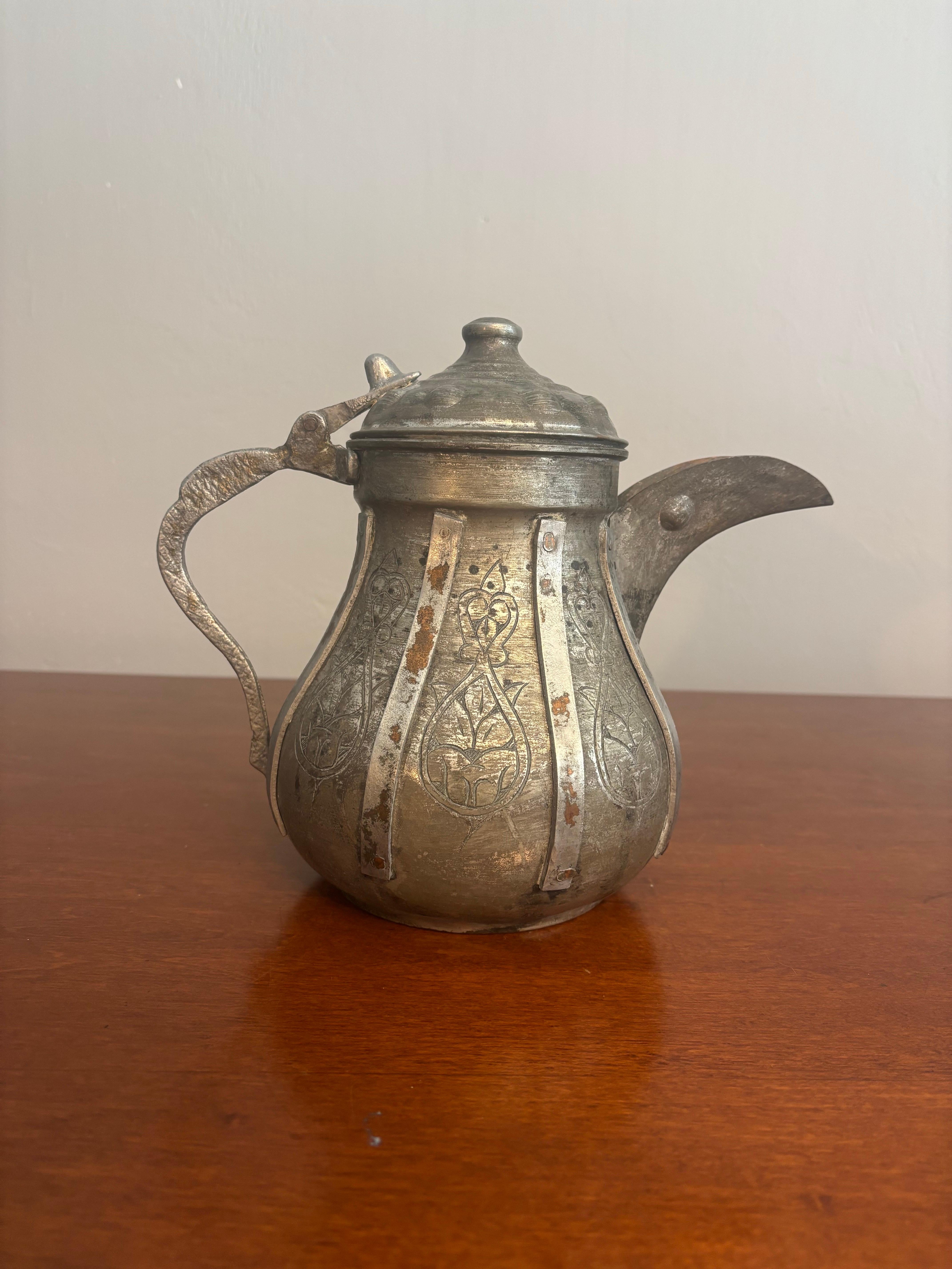 Une magnifique cafetière turque (cezve) façonnée à la main en cuivre et habilement doublée d'étain, présentant des motifs complexes gravés à la main de fleurs stylisées et de motifs géométriques. La forme lobée du corps et ses proportions élégantes