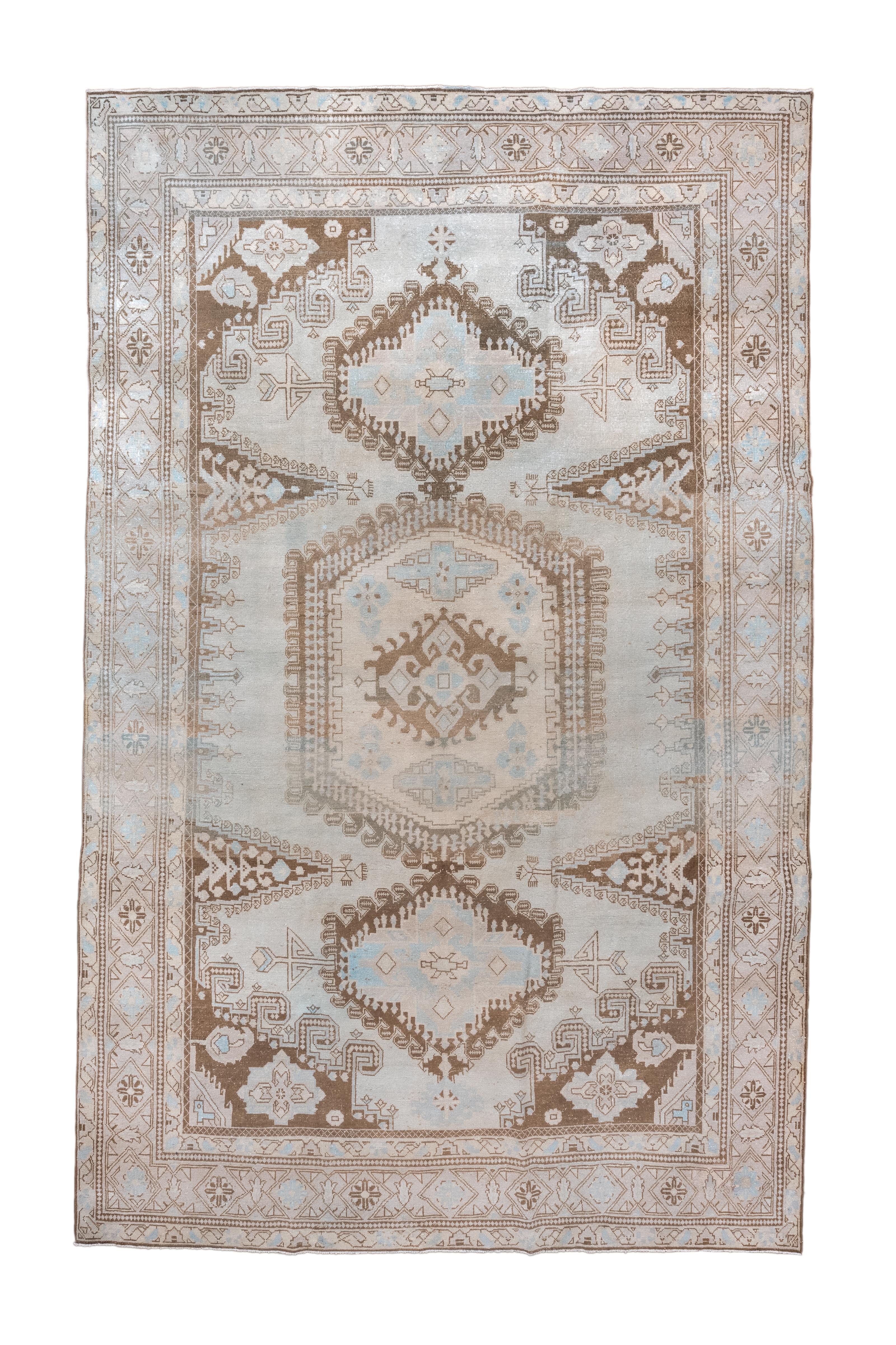 Dieser antike türkische Veece-Teppich, der um 1920 gewebt wurde, zeigt ein auffälliges dreifaches  Medaillon-Layout mit kühnen geometrischen Motiven, eingerahmt von einer dekorativen Bordüre. Rendered  In einer weichen Farbpalette aus Himmelblau,