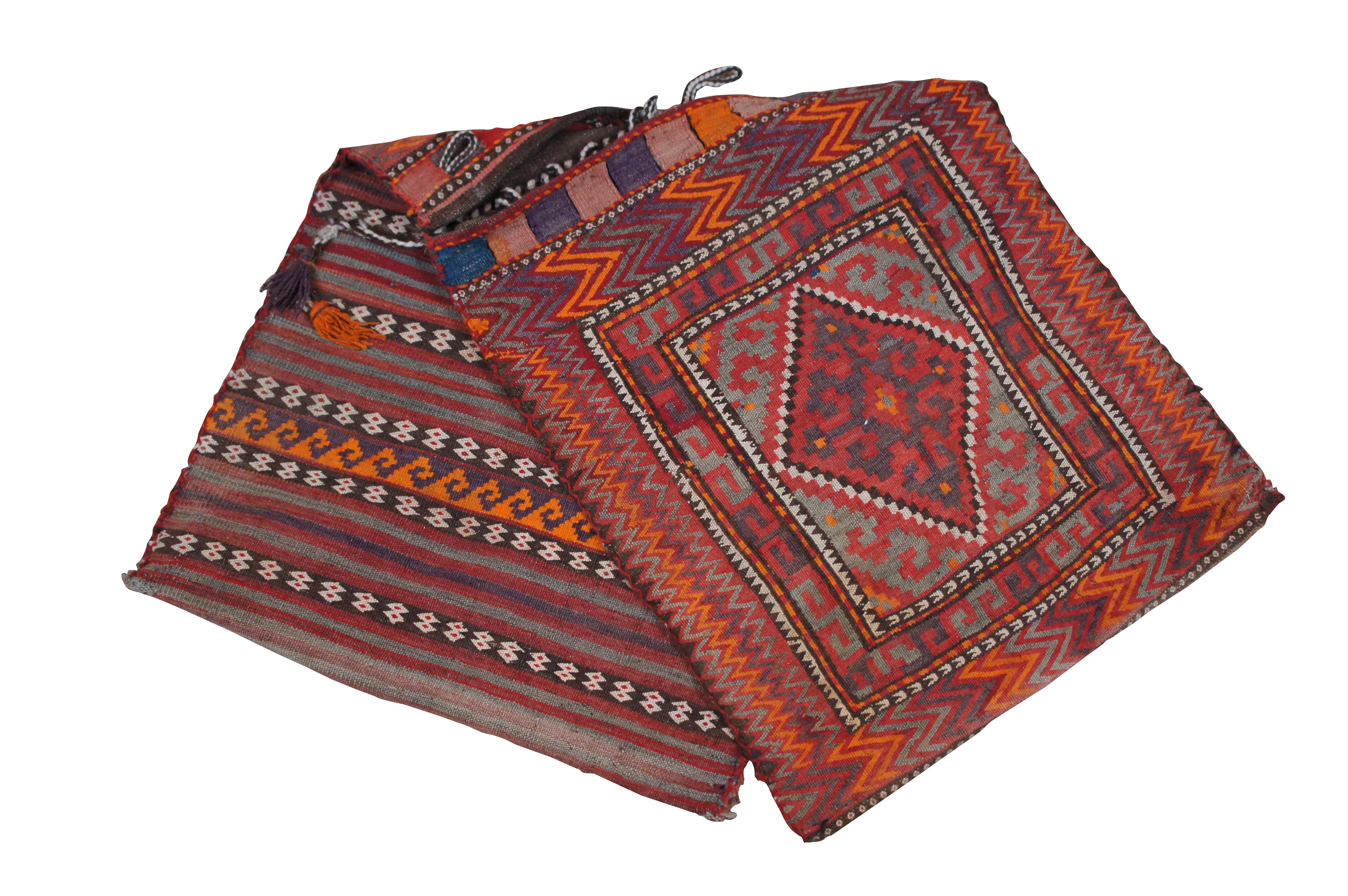 Antique Turkish /  Middle Eastern wool saddle bag, woven with a red, purple, orange and gray striped motif on the back and a geometric kilim tapestry rug design of diamonds, chevrons and Greek key-like meanders on the front. Structured with two