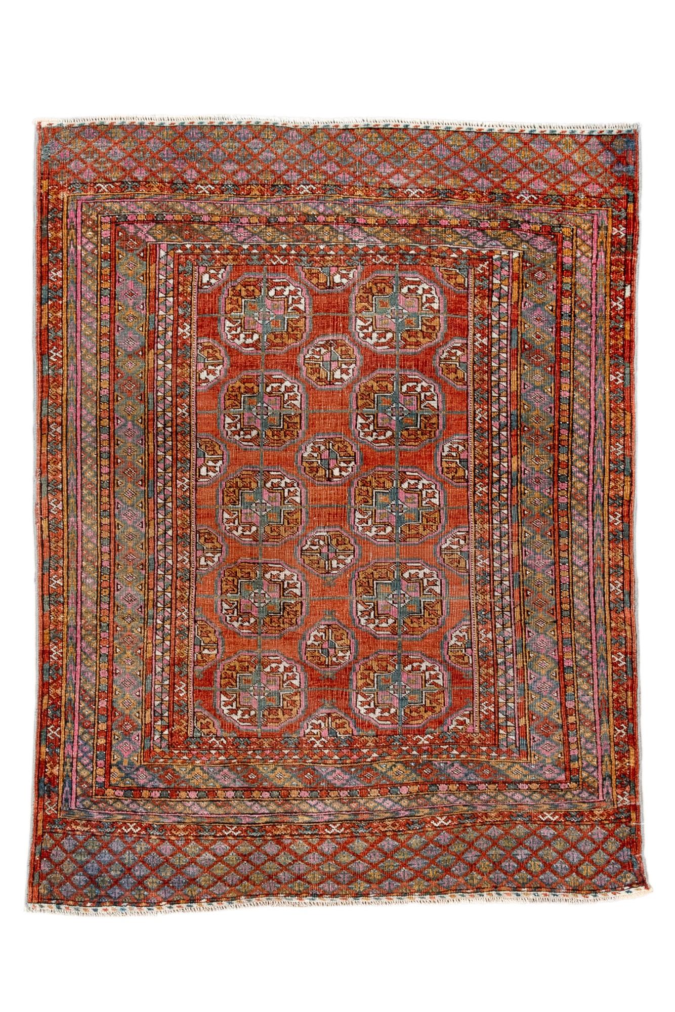  This antique Bokara rug features a classic repeating gül design on a rich terracotta-red field, framed by multiple narrow borders filled with fine tribal motifs. The unusually colorful palette—teal, lavender, rust, and ivory—adds vibrancy while