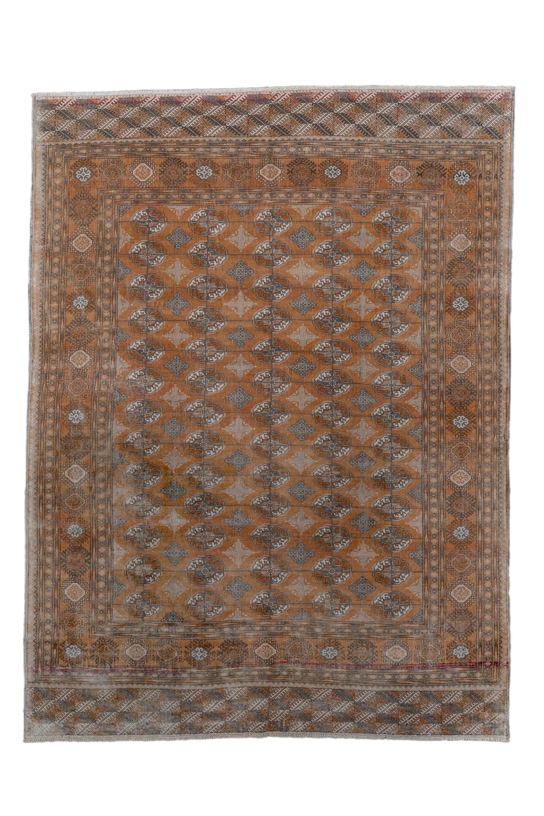This Tekke tribal rug displays five columns of quartered emblematic ovoid tribal guls, with cruciform lozenge Kurbaghe minors set between, all on a red-rust ground. The wide main border is also in red and shows rayed, stellate medallions, enclosing