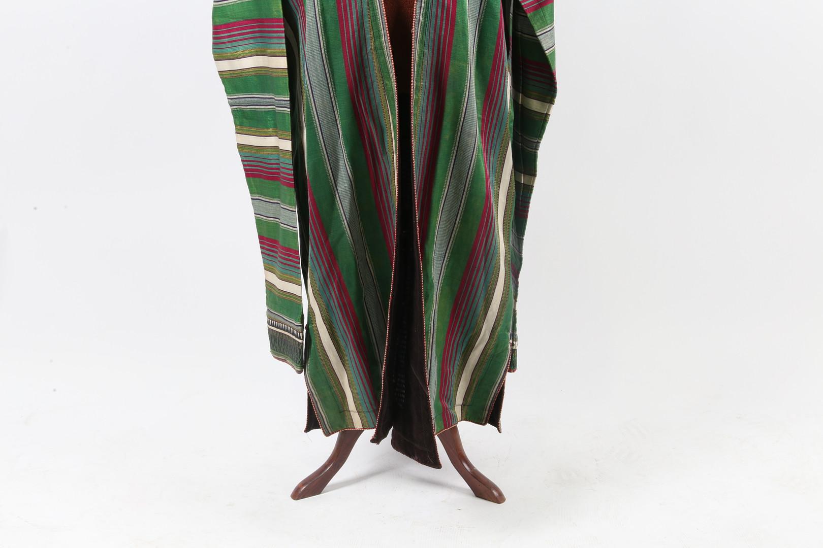 Tejido en pura seda hilada a mano de color verde vivo con rayas crema y magenta, mangas extralargas que denotan un propietario adinerado. Afganistán.
Un chapan de seda (término turcomano para designar un abrigo), ribeteado con finos bordados en el
