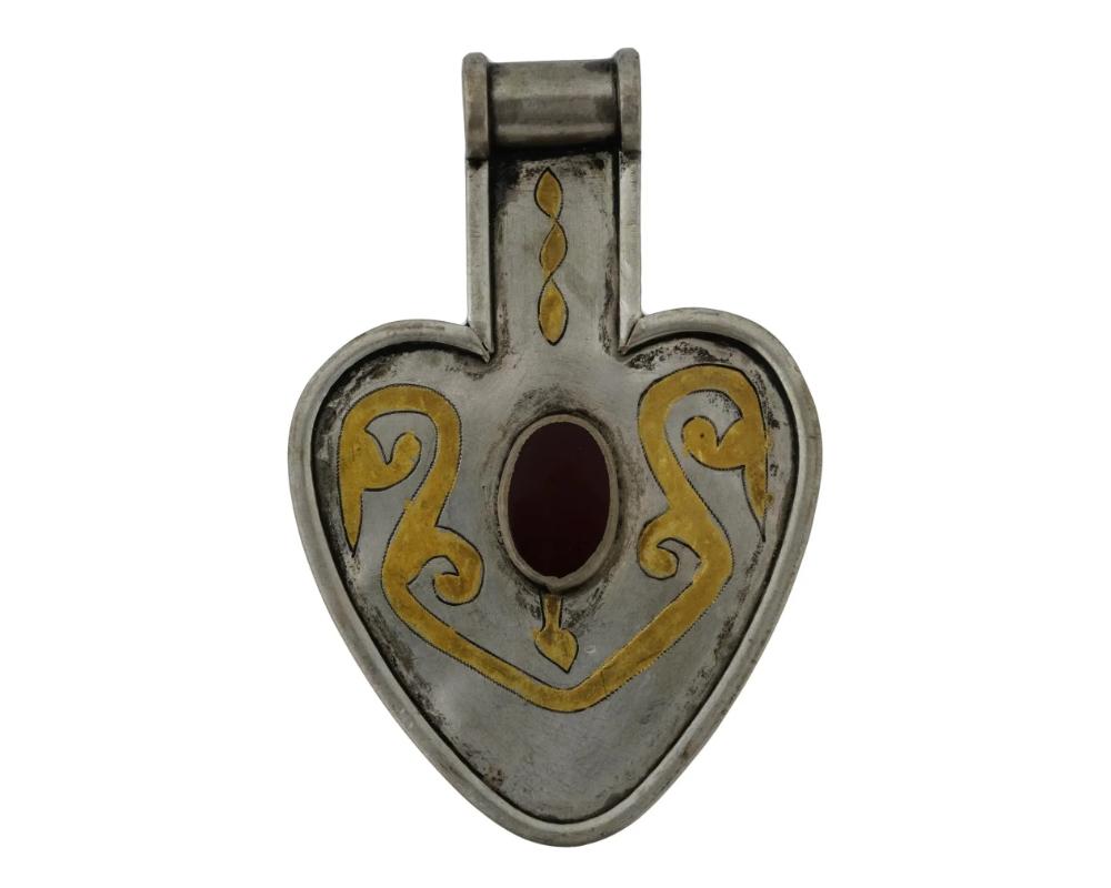Pendentif amulette en forme de cœur en argent turkmène du début du 20e siècle, connu sous le nom d'Asyk. Tribus Yomut, steppes transcaspiennes, Turkménistan. Décor gravé avec détails dorés. La pièce est sertie d'une pierre de cornaline ovale et
