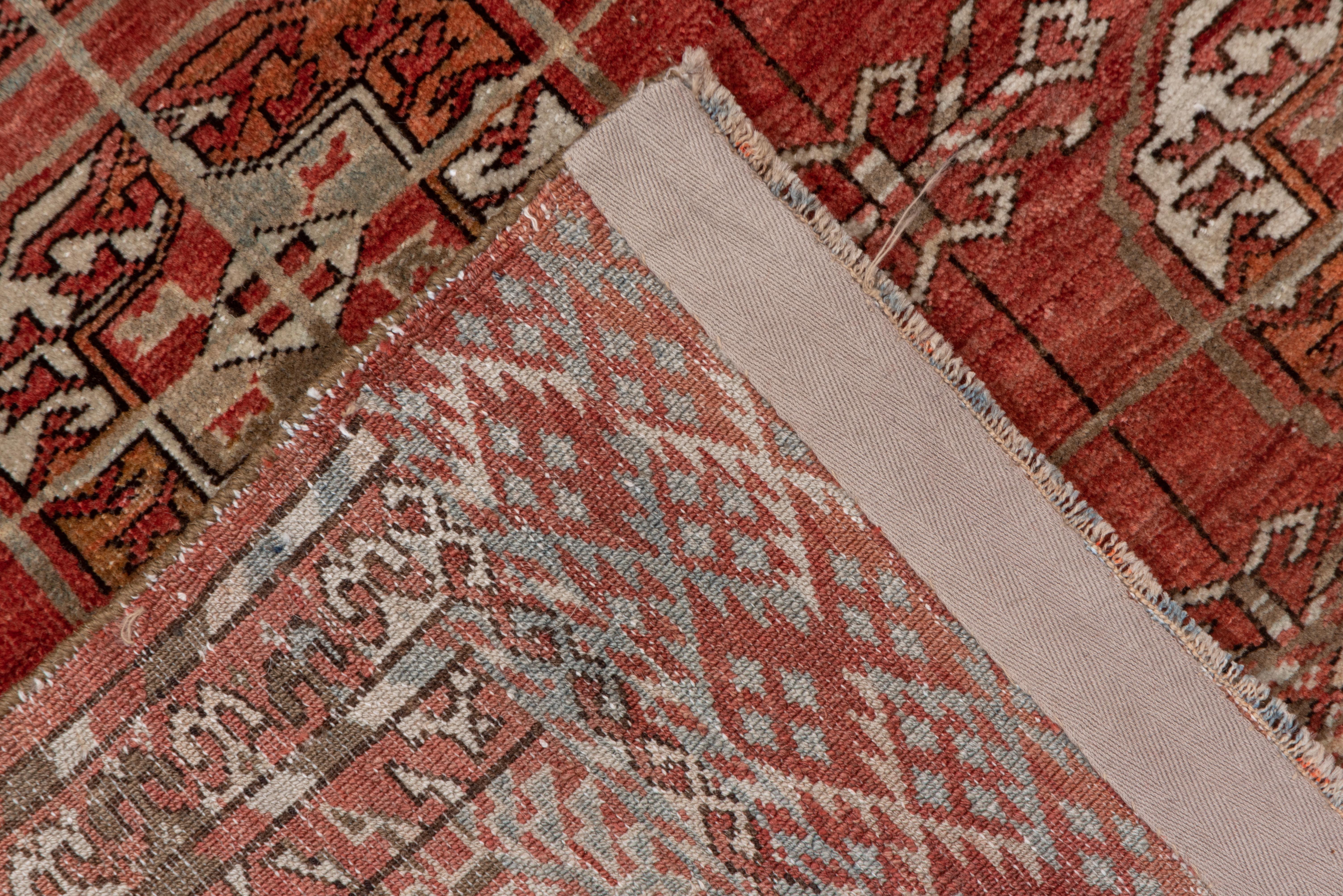 The striated red field of this Central Asian nomadic piece shows a 4 by 8 array of characteristic quartered tribal octagonal guls, bordered by a run of rayed small octagons. At each end is an extra border panel (elem) with a mosaic dot and X-pattern.
