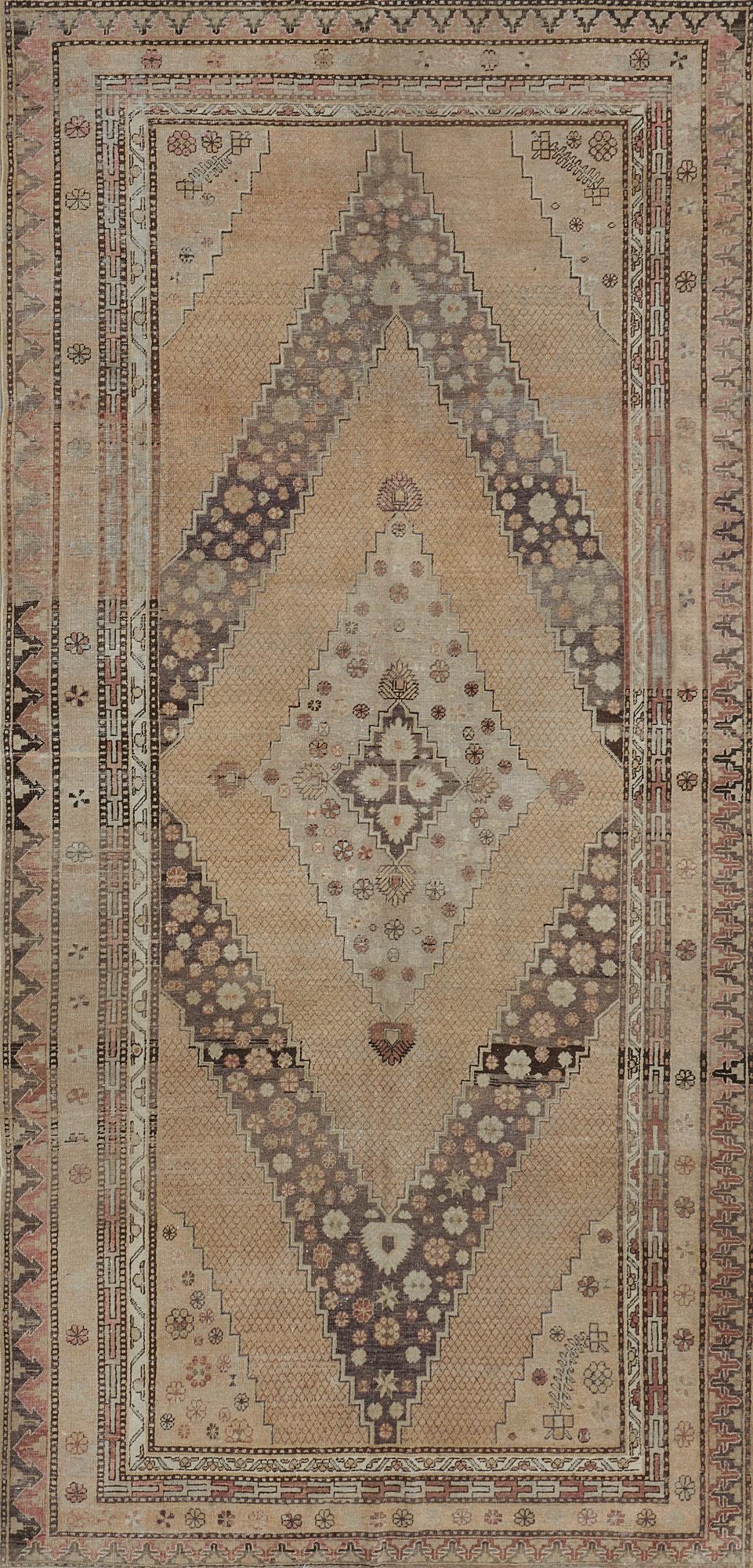 This antique, circa 1900, Khotan rug has a buff-brown field with a delicate fox-brown lozenge lattice around a ivory stepped medallion with palmettes at each side and end containing scattered flowerheads around a mole-brown stepped lozenge medallion