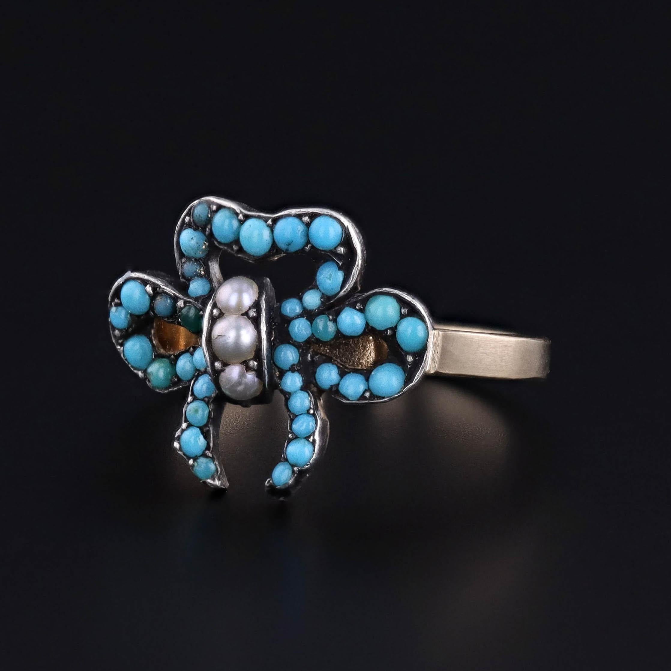 Empreinte de charme victorien et de féminité intemporelle, cette bague ancienne présente un nœud délicatement sculpté, serti de cabochons de turquoise vibrante et de perles naturelles lumineuses, un symbole classique d'amour et de dévotion dans la