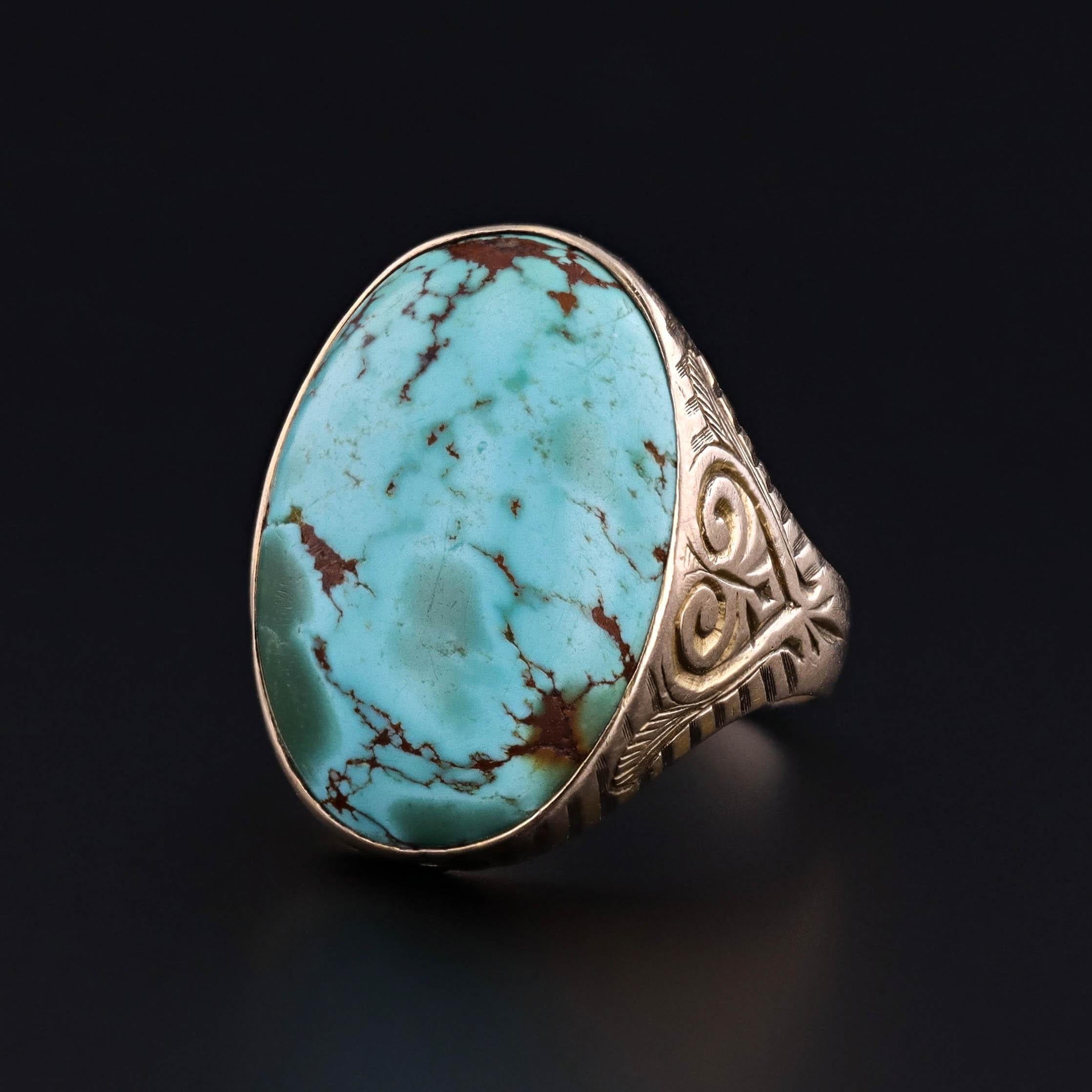 Elegante et pleine de caractère, cette bague ancienne (vers 1910-1920) met en valeur un cabochon de turquoise magnifiquement bombé, serti dans une monture en or 12k finement gravée. Les tons chauds de l'or complètent la teinte bleue vibrante de la