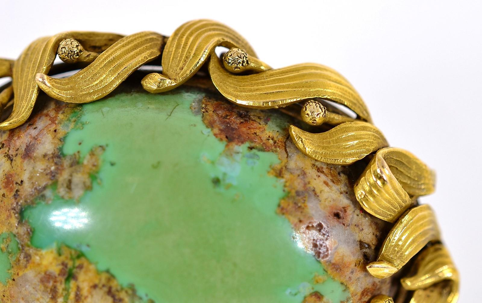 A unique Art Nouveau  natural green Turquoise oval brooch.   The Turquoise flaunts its organic golden inclusions and is set in a 14KT yellow gold frame of flowing leaves, enhanced by a time worn soft patina.  The brooch can also be worn as a