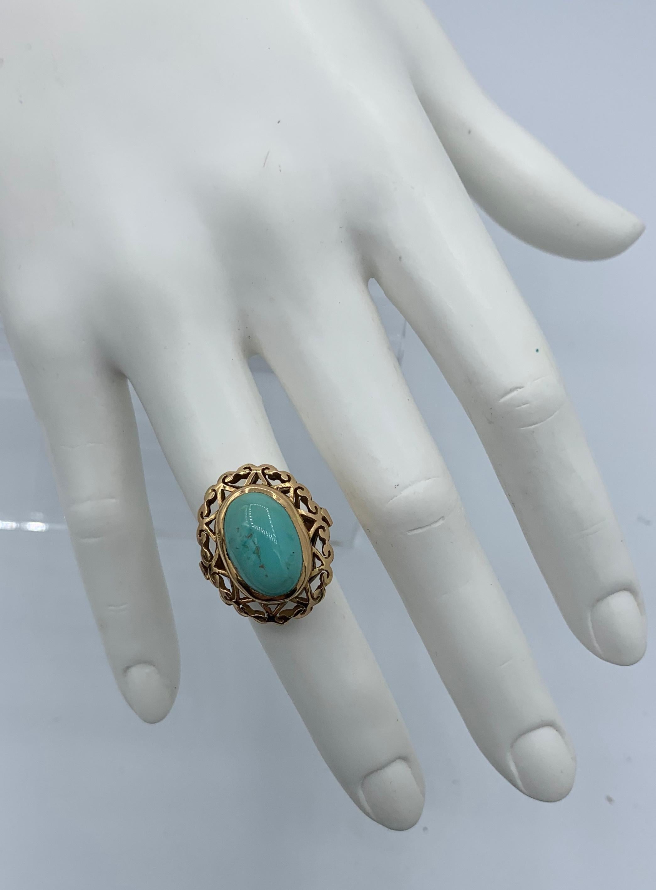 This is a gorgeous antique Turquoise Ring with a stunning 15mm by 11mm Turquoise Cabochon.  The Turquoise is set in a wonderful open work scroll motif border setting in 18 Karat Yellow Gold.  The vivid oval Turquoise cabochon is of such lovely color