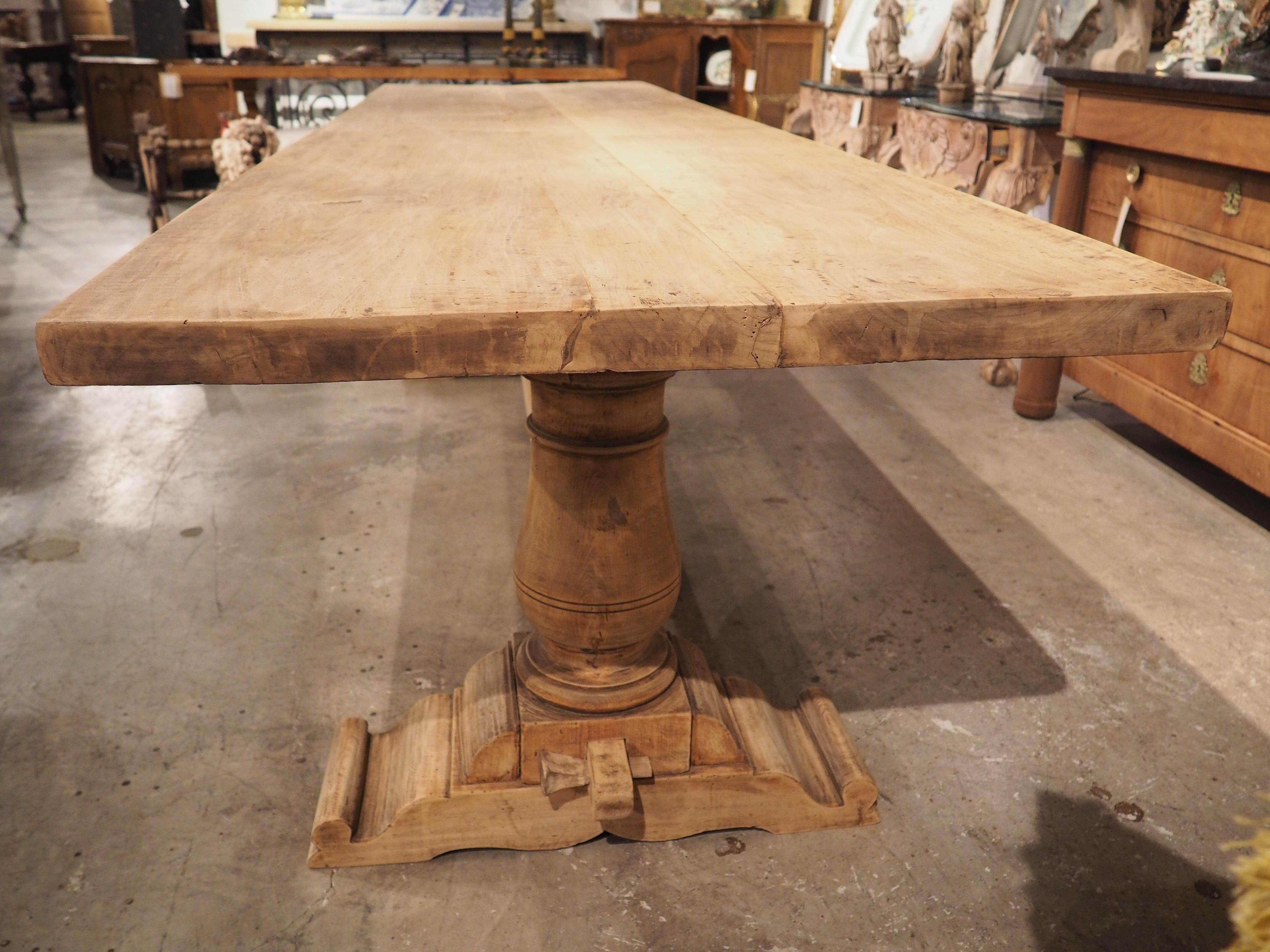 A handsome and robust table with a thick baluster form trestle base, this dining table was hand-carved in Tuscany, Italy, circa 1900, using both walnut and oak. The original finish has been stripped, allowing the natural wood grains to add to the