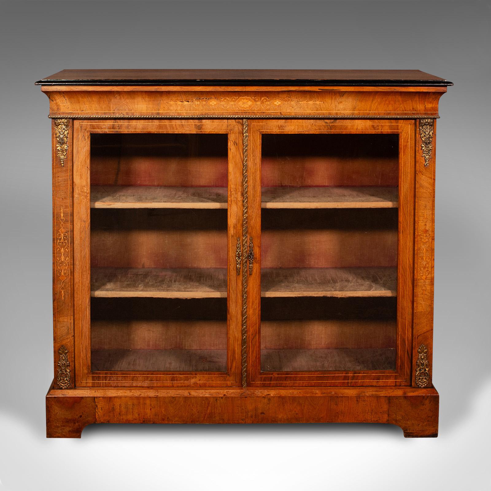 This is an antique twin pier cabinet. An English, walnut glazed bookcase, dating to the Victorian period, circa 1870.

Of superb appearance and craftsmanship, with appealing detail
Displays a desirable aged patina and in good order
Select walnut
