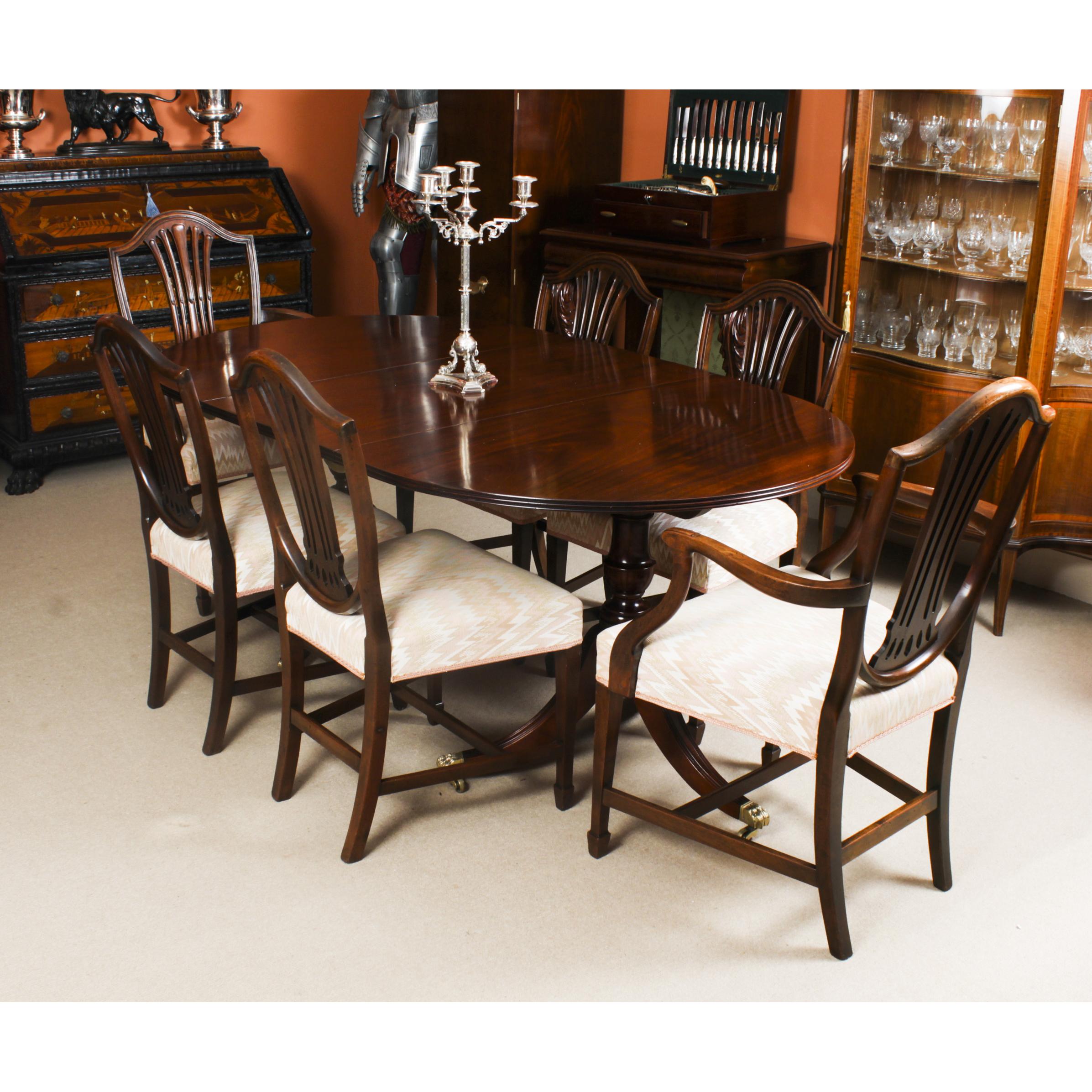 This is an elegant dining set comprising an antique Regency dining table C1830 in date with a set of six Shield back dining chairs.

The table is of oval form with reeded edge. It is raised on twin urnular pillars with triple swept sabre leg bases
