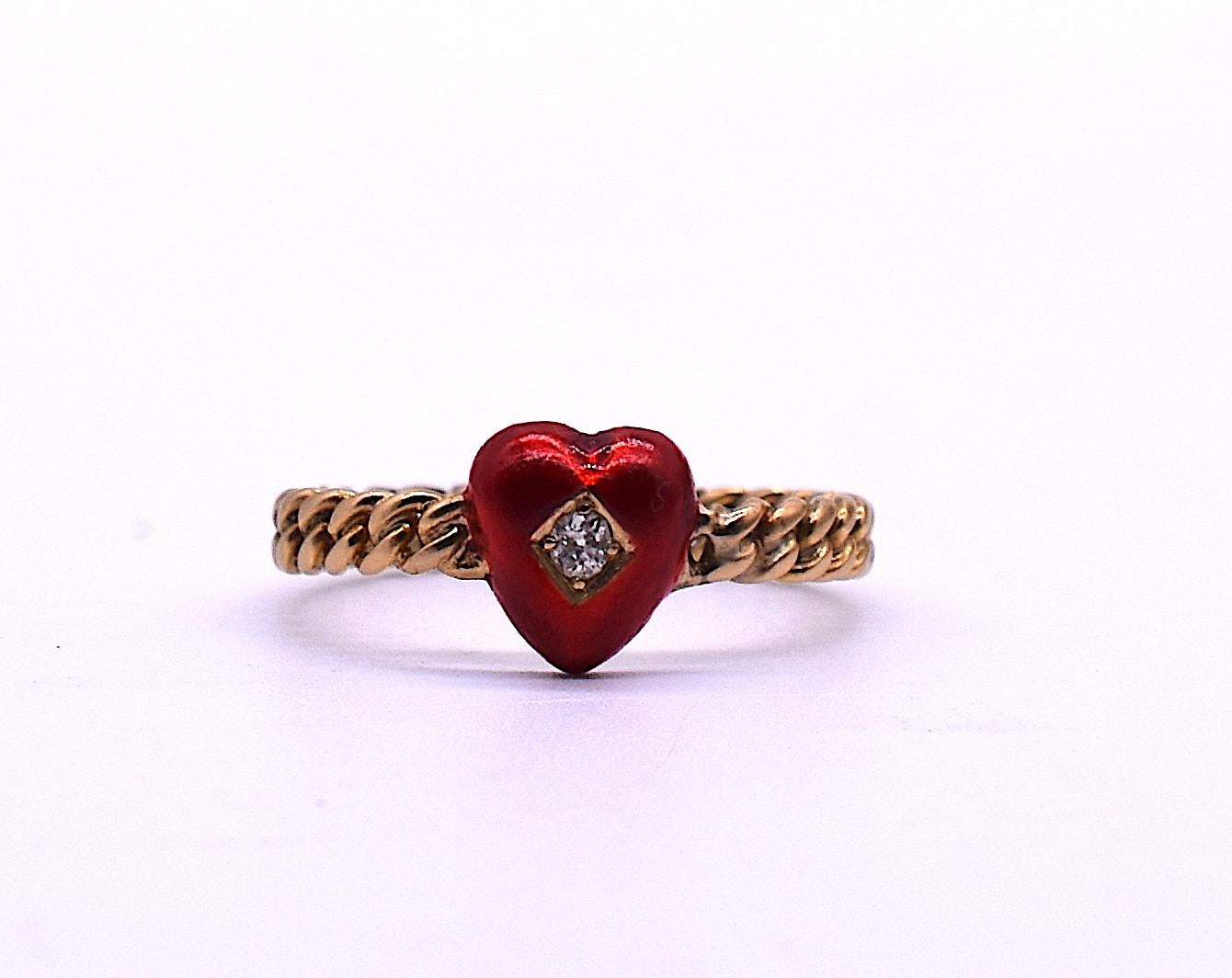18K Edwardian gold band ring featuring a lovely enamel red heart with a round diamond embedded in a diamond shape at the center. The ring is enhanced by its the twisted rope band. We love the burst of color the little red heart adds as well as the