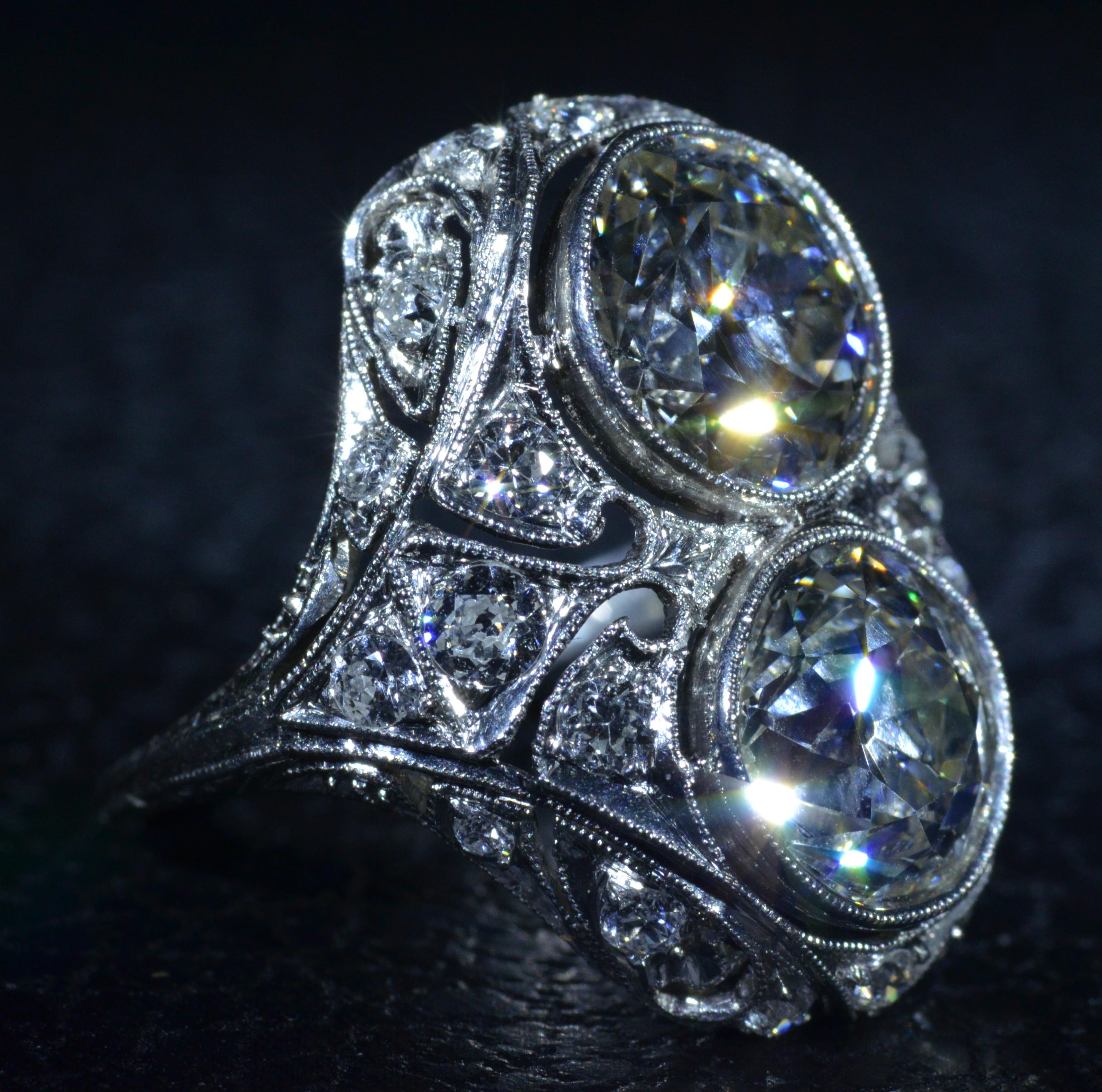 Antique Two Diamond Platinum Filigree Ring.  The ring is a set with a 2.30 carat old mine cut diamond and a 2.48 carat old mine cut diamond.  The diamonds have an approximate Gemological Institute of America clarity grade of Vs1 and Vs2 and a color