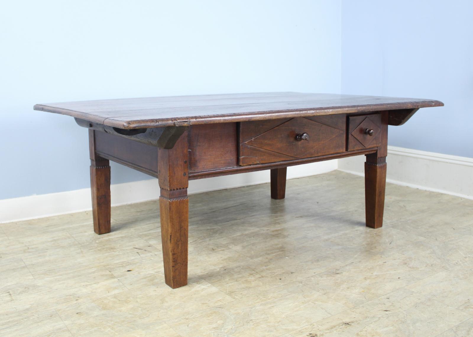 A handsome Alsacian cherry coffee table with a glossy, patinated top and sturdy tapered legs with carved detail. Nice deep cherry color and interesting grain. The unusual different size drawers on the front are unique and give an good look. One of