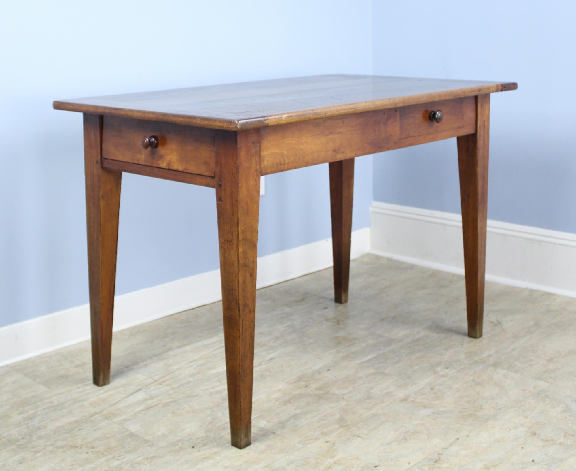 A graceful French antique writing table in vibrant cherry. Elegant tapered legs, breadboard ends and a comfortable 24