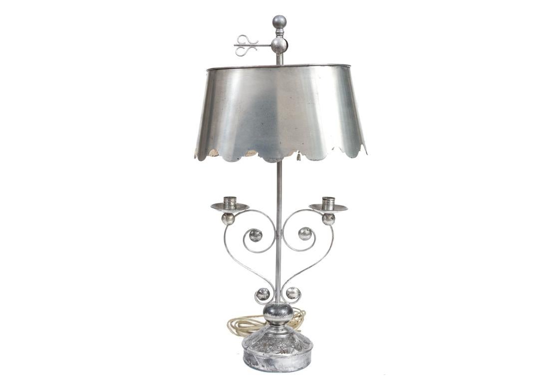 Eine Geldstrafe  antike Tischlampe auf rundem Fuß in Volkskunstqualität mit verschnörkelten Armen in Form eines Schmetterlings, gekrönt von zwei Düsen und Wachsnäpfen unter einem angeschnittenen  ovaler, verstellbarer Metallschirm mit