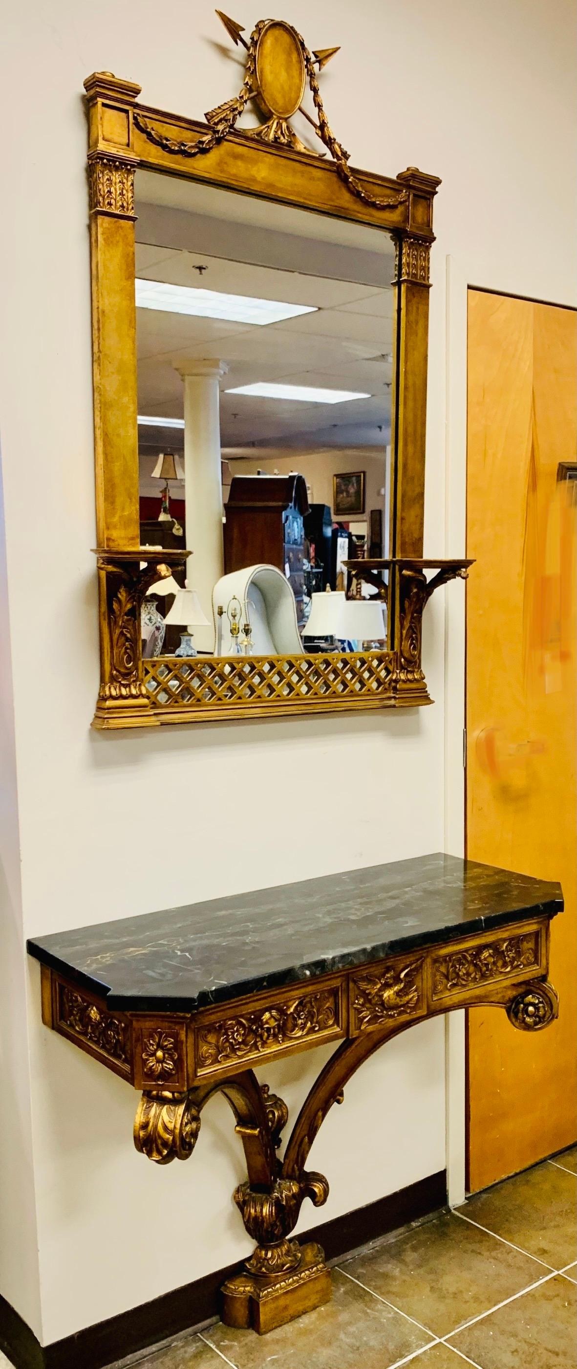 Antique 19th century ornate 2 pc carved gold giltwood console table with intricately carved motif of birds and faces. It has a thick marble top and attaches to the wall. The mirror features attached wall brackets on each side and a crest with an