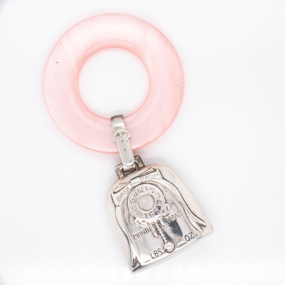 A fine antique baby rattle.

In sterling silver.

By Web.

With the rattle mounted on a pink 
