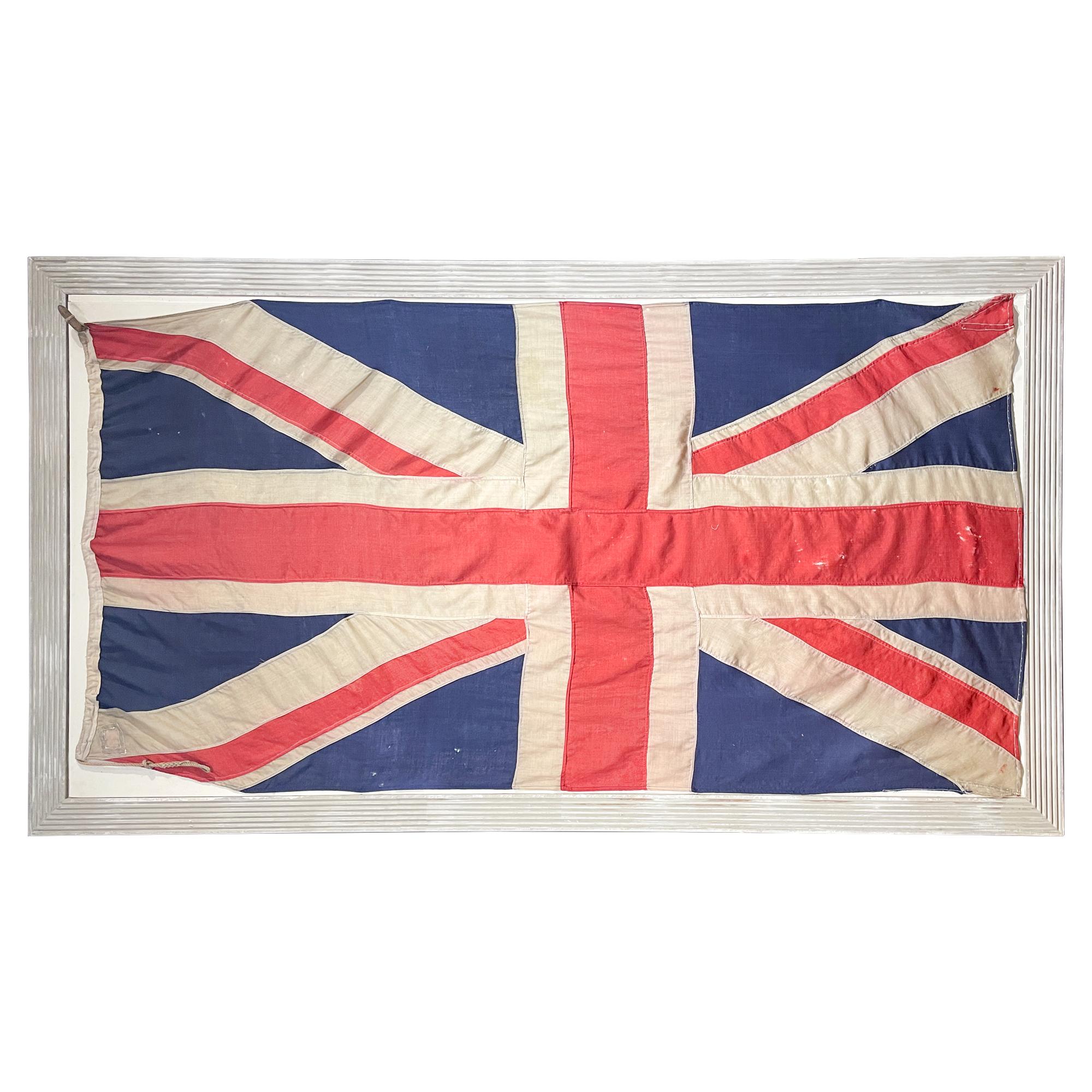 This large-scale antique Union Jack was sourced in England and has been mounted on a fluted wood frame in a pained greige finish. This frame can be hung either portrait or landscape orientation, as D-rings have been installed to accommodate either.