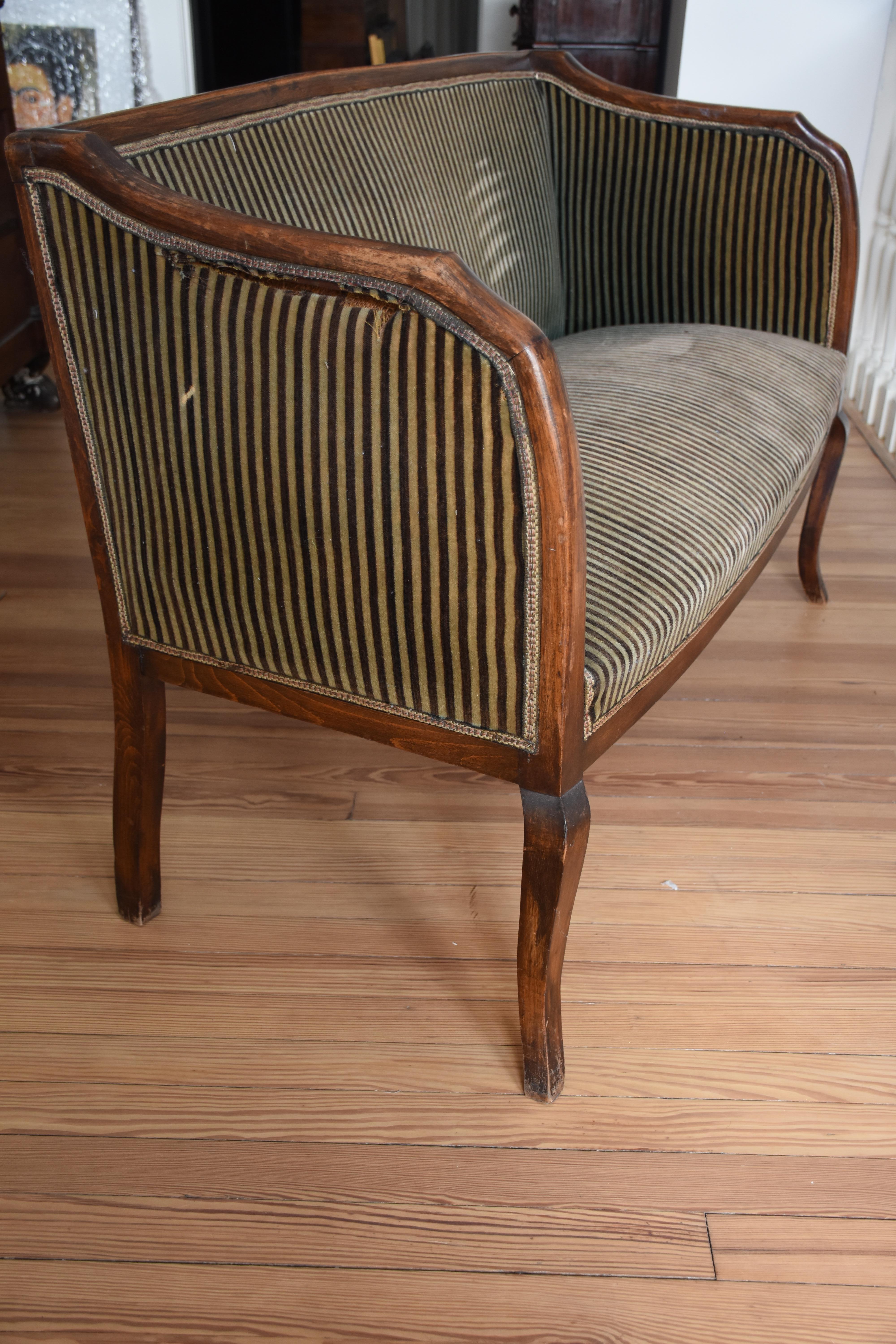 Diese elegante Polsterbank aus dem frühen 20. Jahrhundert zeichnet sich durch exquisite Handwerkskunst und zeitloses Design aus. Der fein geschnitzte Holzrahmen mit anmutig geschwungenen Armen und Beinen im Cabriole-Stil unterstreicht die