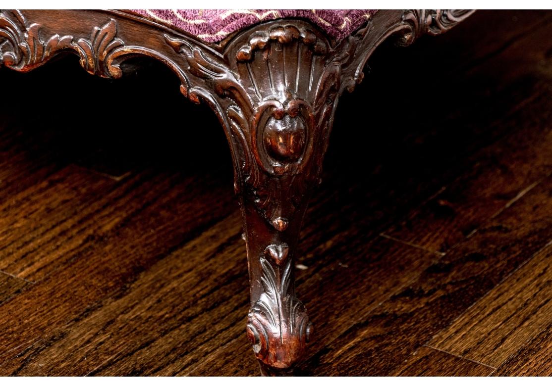 Elle repose sur des pieds en acajou sculpté en forme de dos de chameau et sur des accoudoirs roulés avec de l'acajou sculpté apparent à travers les accoudoirs. Coussin d'assise unique, non rembourré, avec motif géométrique répétitif décoratif sur un