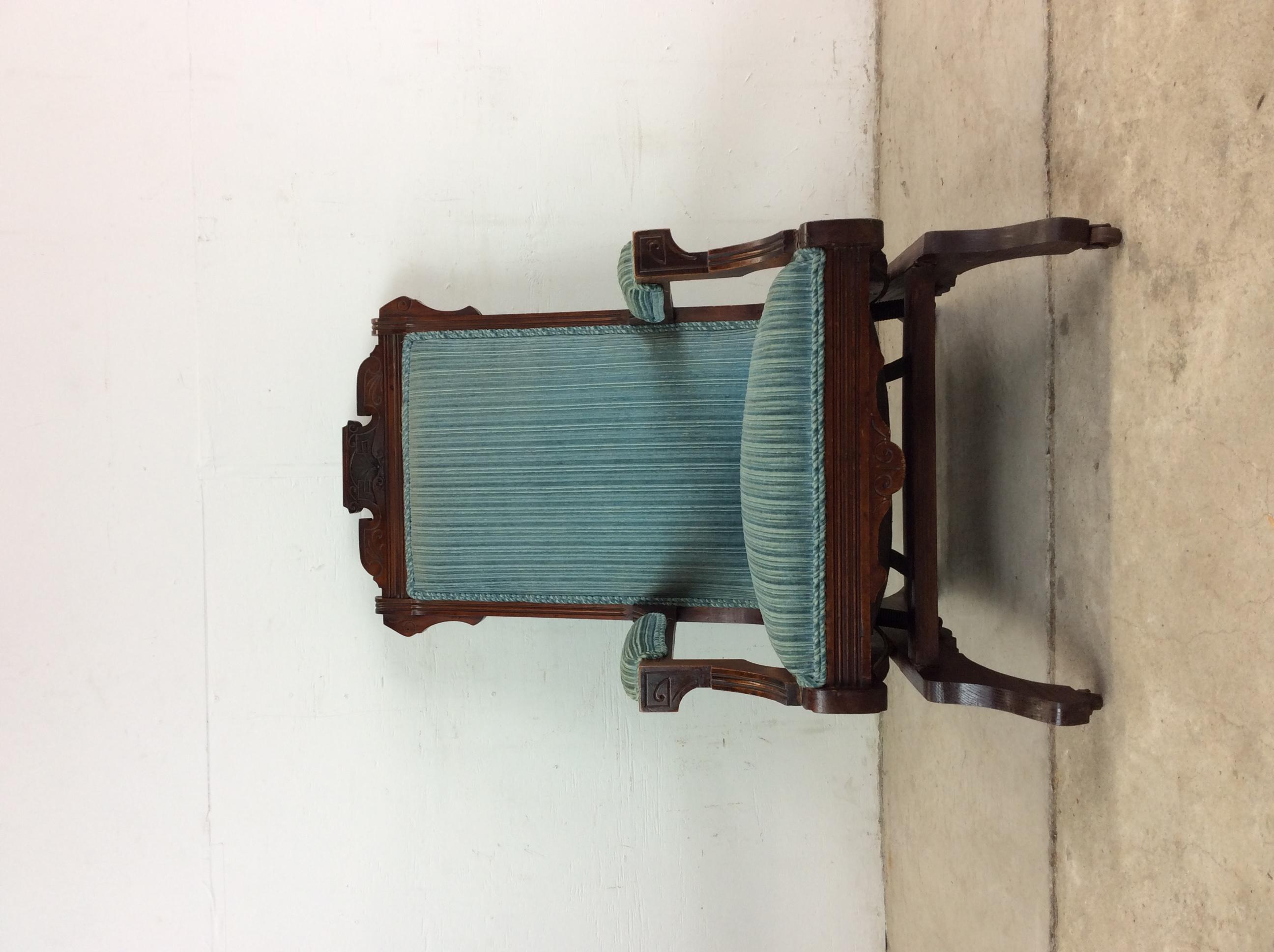 This antique rocker / glider features hardwood construction, original dark finish, vintage blue upholstery on seat and arms, carved wood detailing throughout, and rocker glider base with original castor wheels.

Dimensions: 24w 32.5d 38h 21.5ah 15sh