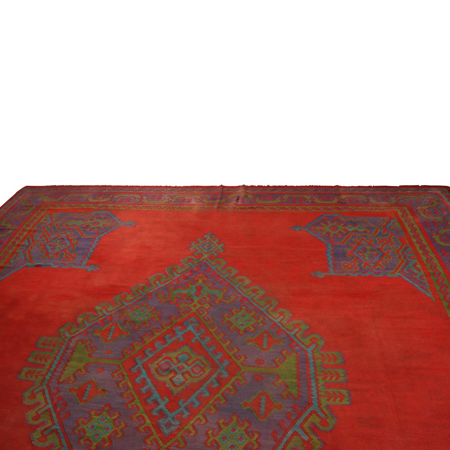 Originating from Turkey between 1890-1900, this antique Usak Kilim rug enjoys an engaging array of red, indigo, and green colorways, the latter accenting the former in marriage to the ornate-meets-Minimalist geometric design complementing this