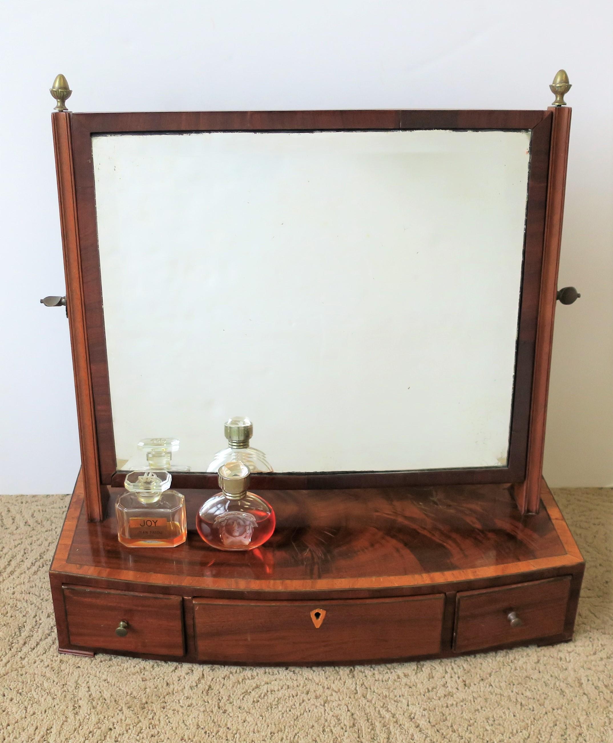 A beautiful and rich antique vanity or dressing mirror with three draws, circa 19th - early 20th Century. Mirror is square with beveled edge, directional flexebilty (north and south), and brass finials on top on both sides. Left and right side draws