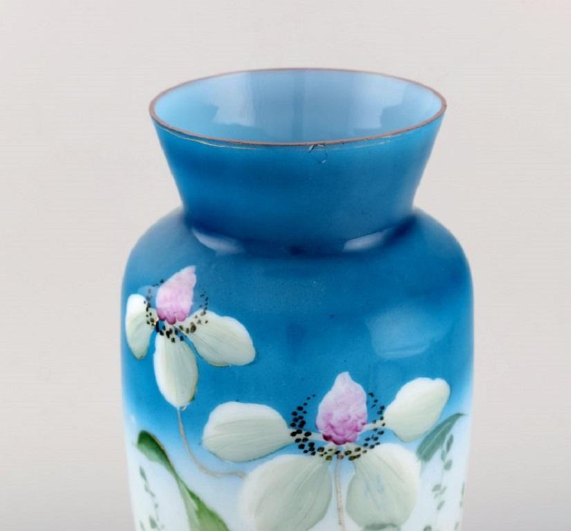 Antique vase in mouth-blown opal art glass with hand-painted flowers and foliage on a blue background, 
circa 1900.
Measures: 32 x 16.5 cm.
In very good condition. Small chip.