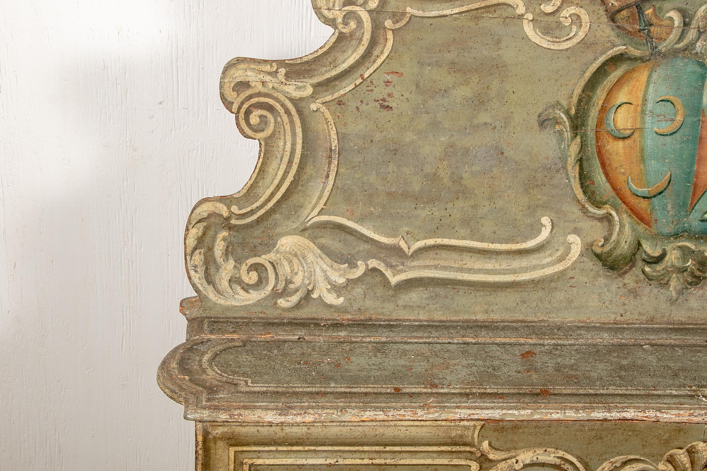 With a tall scrolled back and scrolled lower frame. In the Classic Venetian sage green paint with white scrolls and a large polychrome painted crest on the back. The bench platform lifts up for storage inside, with an escutcheon on the front shell