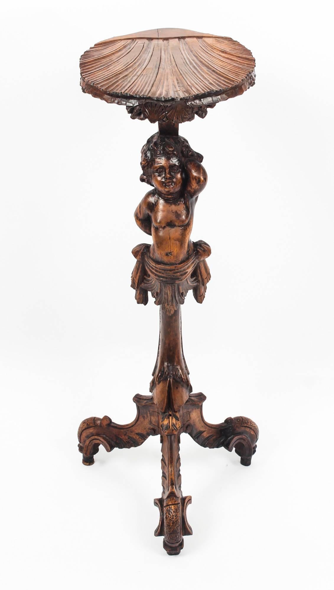 This is a beautiful antique Venetian, carved walnut cherub torchere in the Rococo revival style, circa 1820 in date.

The shell-shaped tray top is held aloft by a carved cherub an raised on a scrolling tripod base.

It is a very beautiful piece