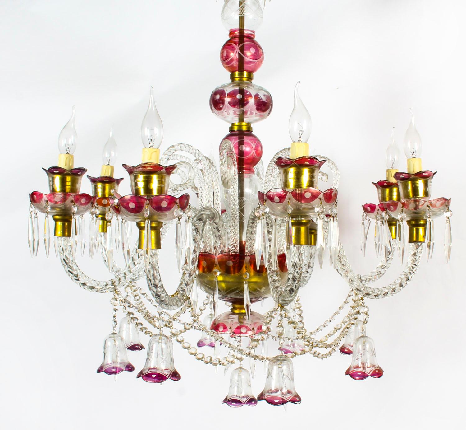 This is a beautiful antique Venetian crystal chandelier with eight lights circa 1900 in date.

The delicate and elaborate hand blown clear crystal with cranberry red highlights. The chandelier features eight scrolled sconces, each arm adorned with