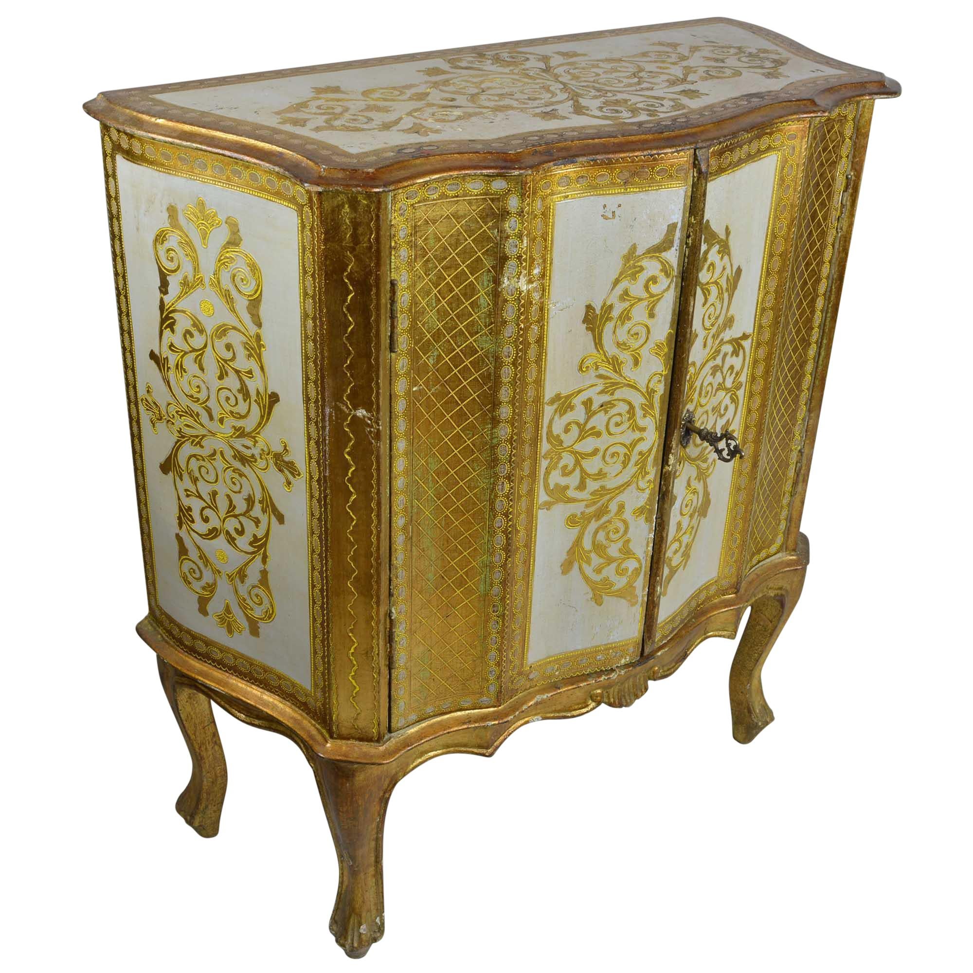 Antique cabinet that will work fabulous as a dry bar that will fit in the smallest of spaces. The detail of the gold giltwood pops off the creamy white background, The detail carries over to sides and makes a statement from any angle, even the