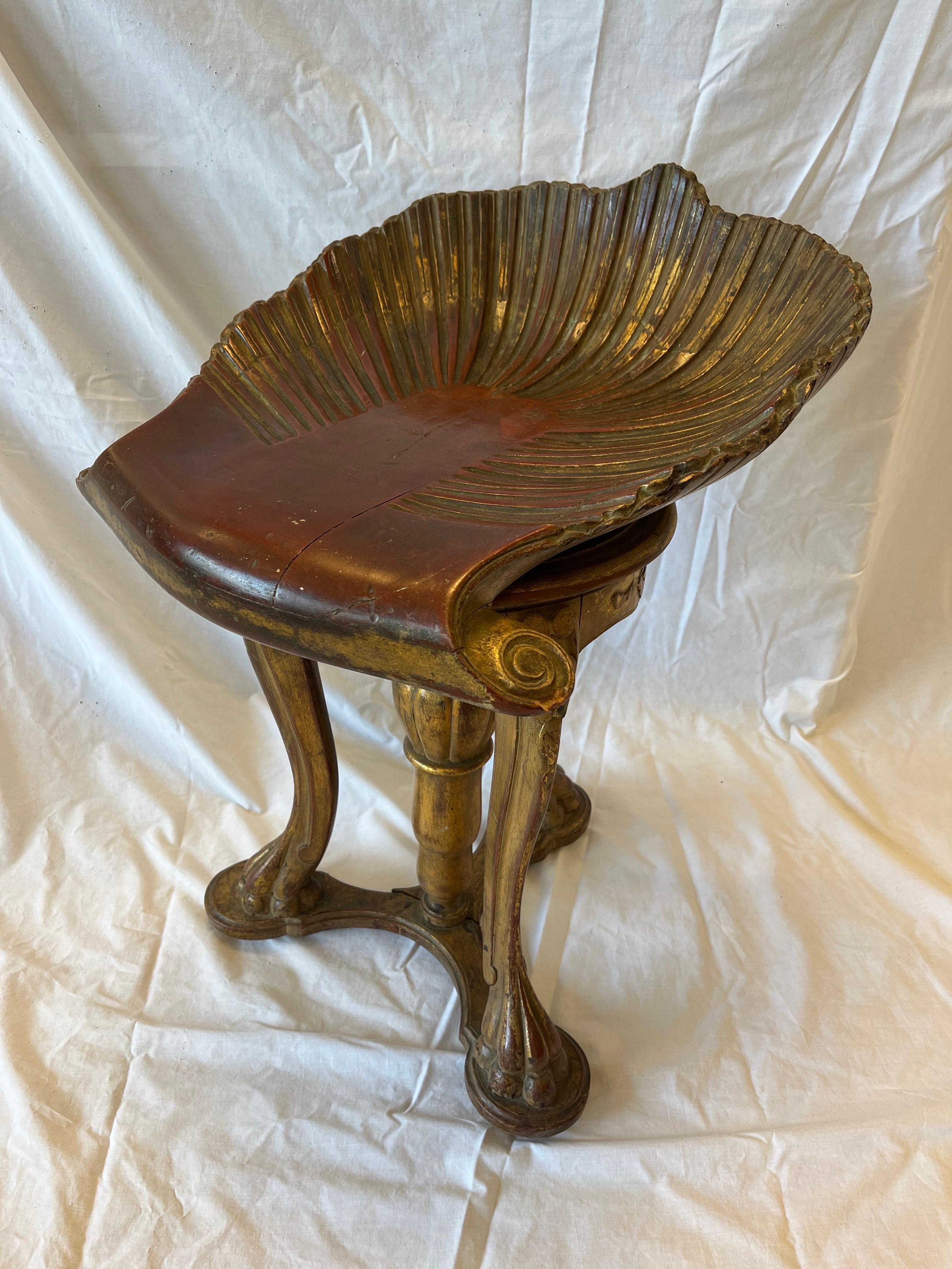 An antique late 19th or early 20th century Ventian Italian grotto style carved and gilt and polychromed shell stool. This piano stool, or a stand alone stool as a piece of furniture in your home, exhibits beautiful character and wear. The red bole