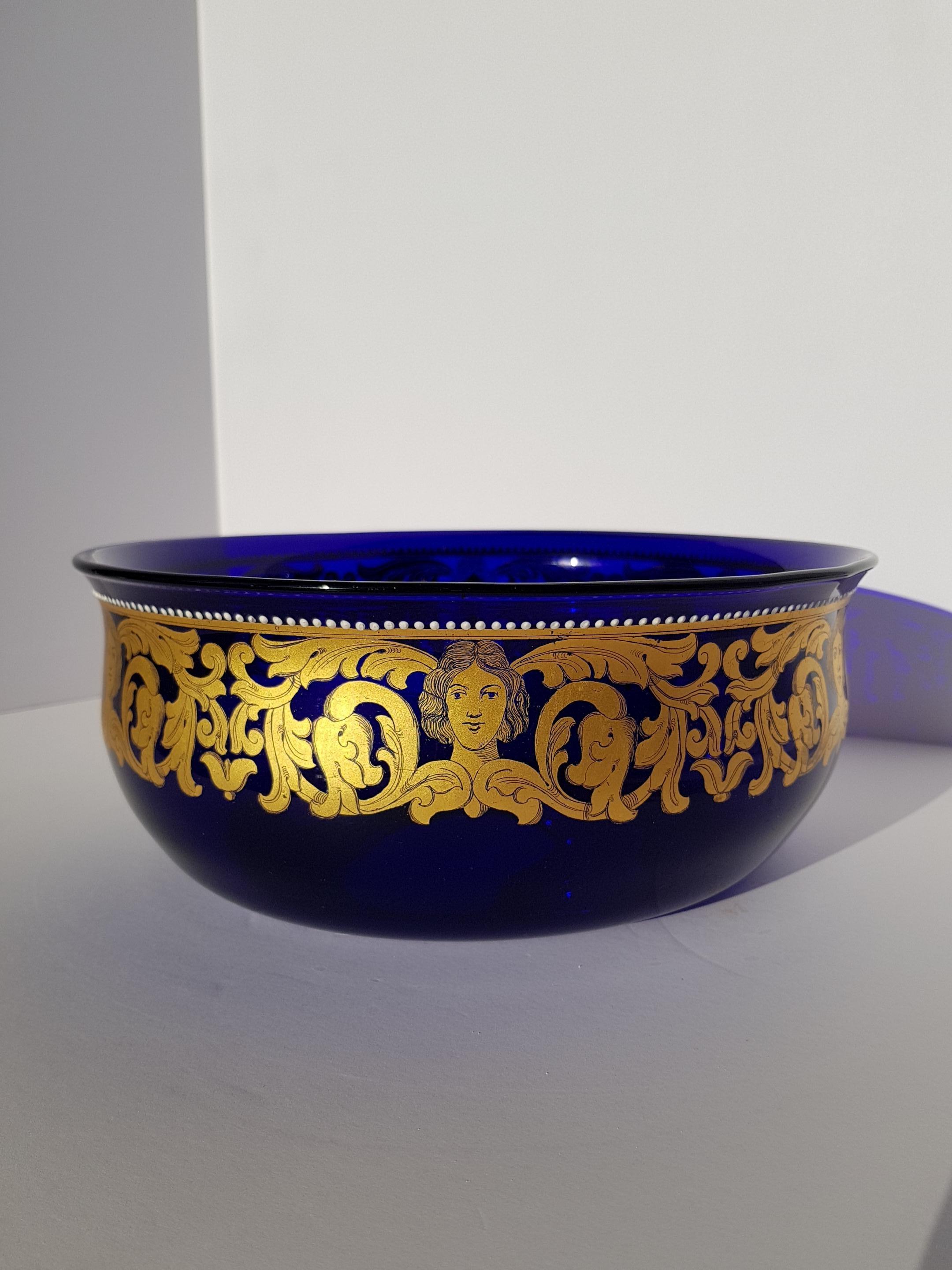 A rare, large and unique antique Venetian Murano art glass bowl or centerpeice hand blown from the finest rich royal blue murano glass and hand enamelled with 24k gold leaf. Scroll vines and leaves adorne this art glass bowl along with human heads