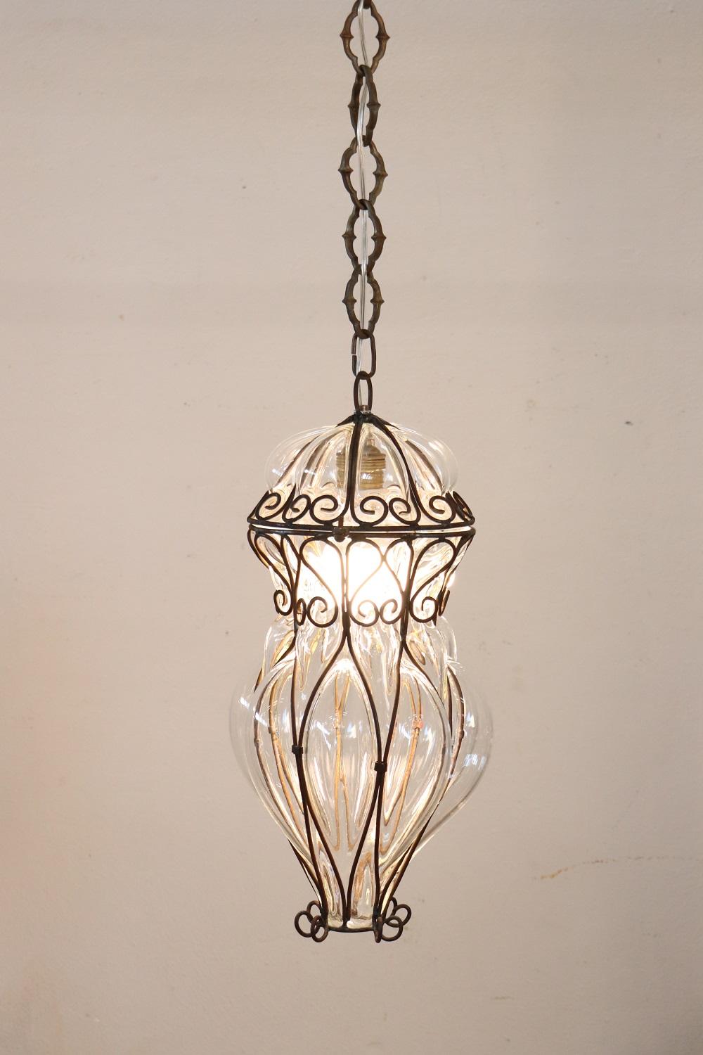 Lovely early 20th century antique venetian pendant light with one internal bulb. This fantastic pendant made by Venetian master craftsmen of mouth-blown glass. In transparent glass with a delightful iron frame which has various curls and swirls, it