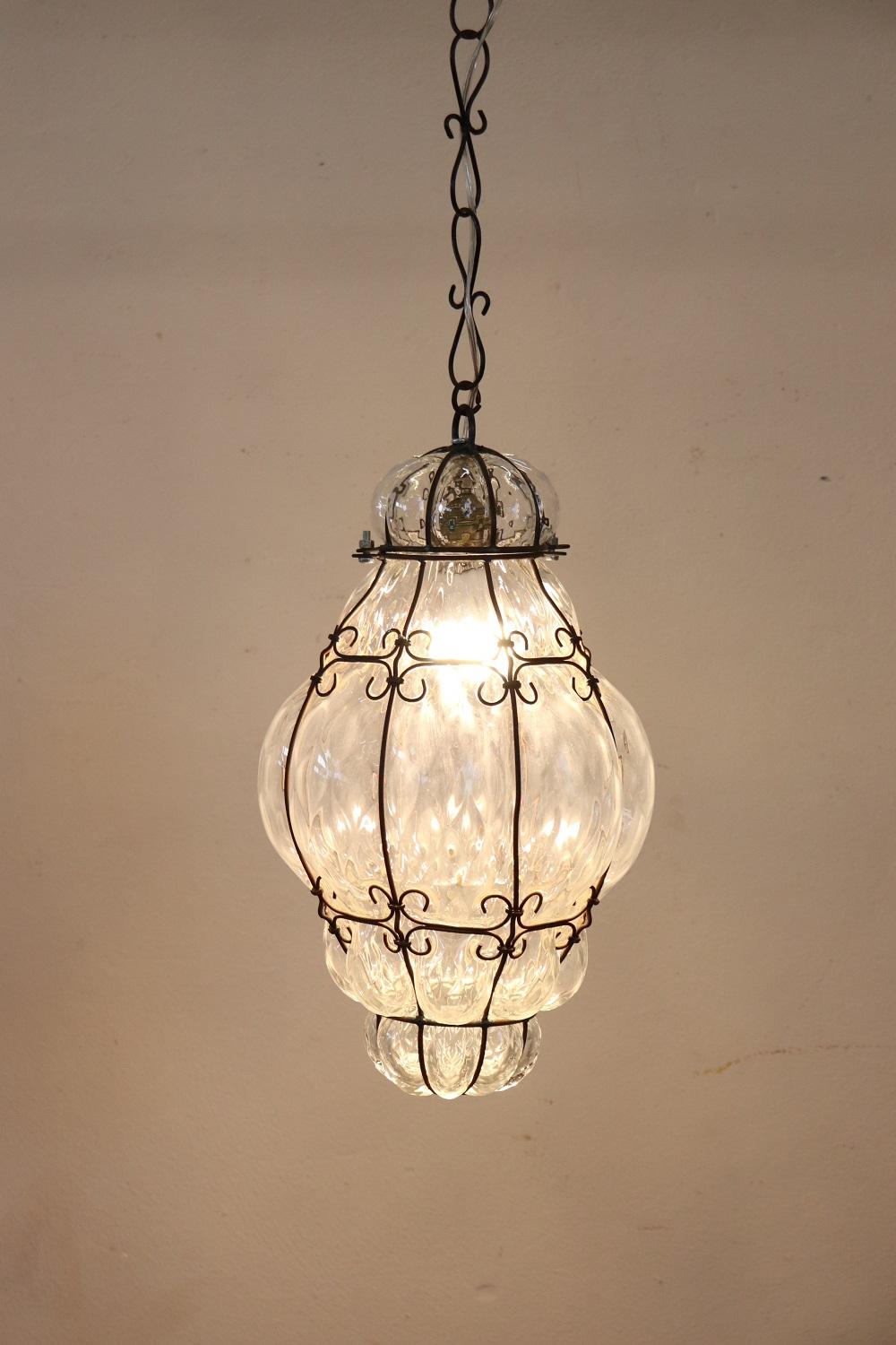Lovely early 20th century antique venetian pendant light with one internal bulb. This fantastic pendant made by Venetian master craftsmen of mouth-blown glass. In transparent glass with a delightful iron frame which has various curls and swirls, it