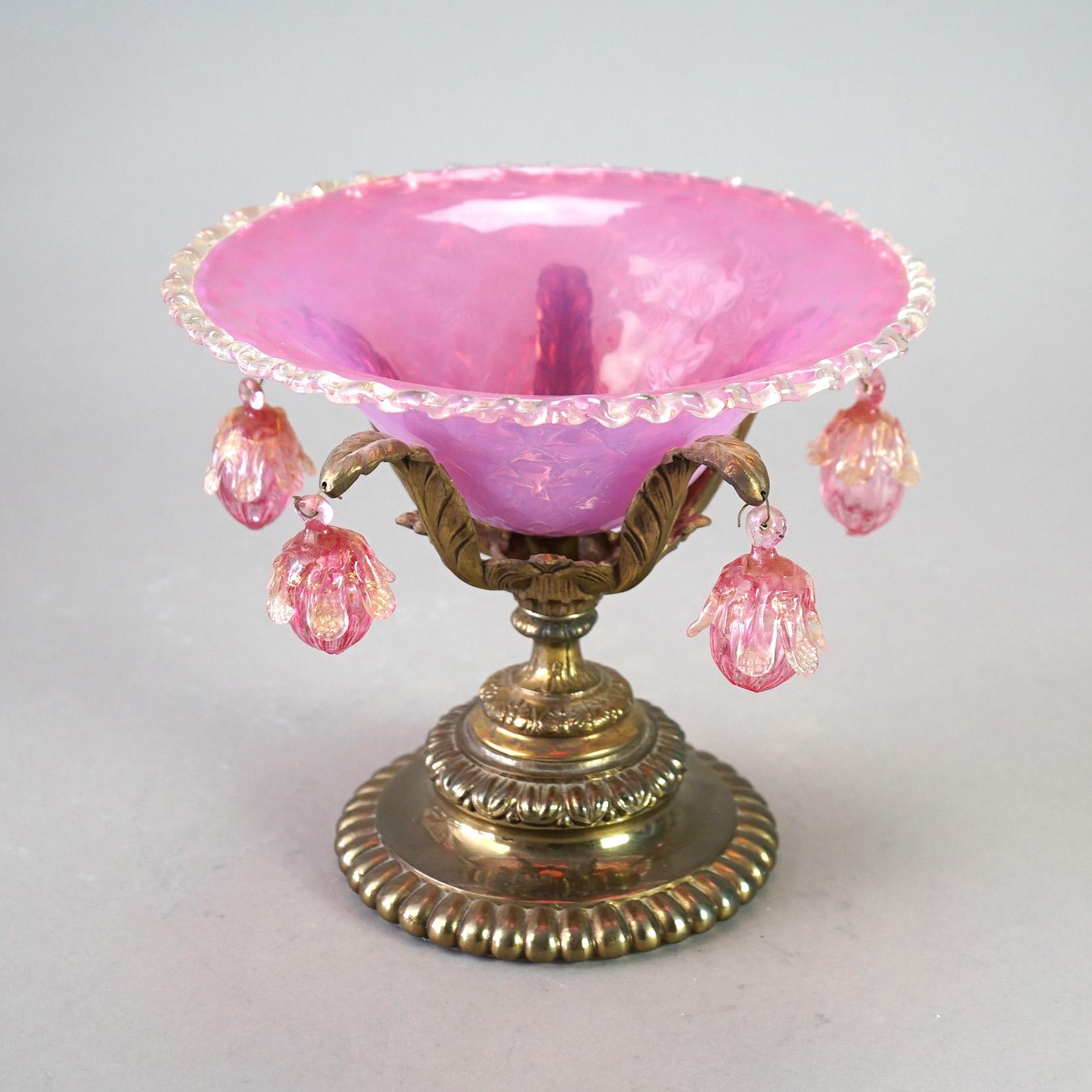 An antique Venetian compote offers Murano pink glass bowl having ruffled rim seated in foliate form cast base with hanging blown glass ornaments, c1890

Measures- 8.75''H x 10''W x 10''D