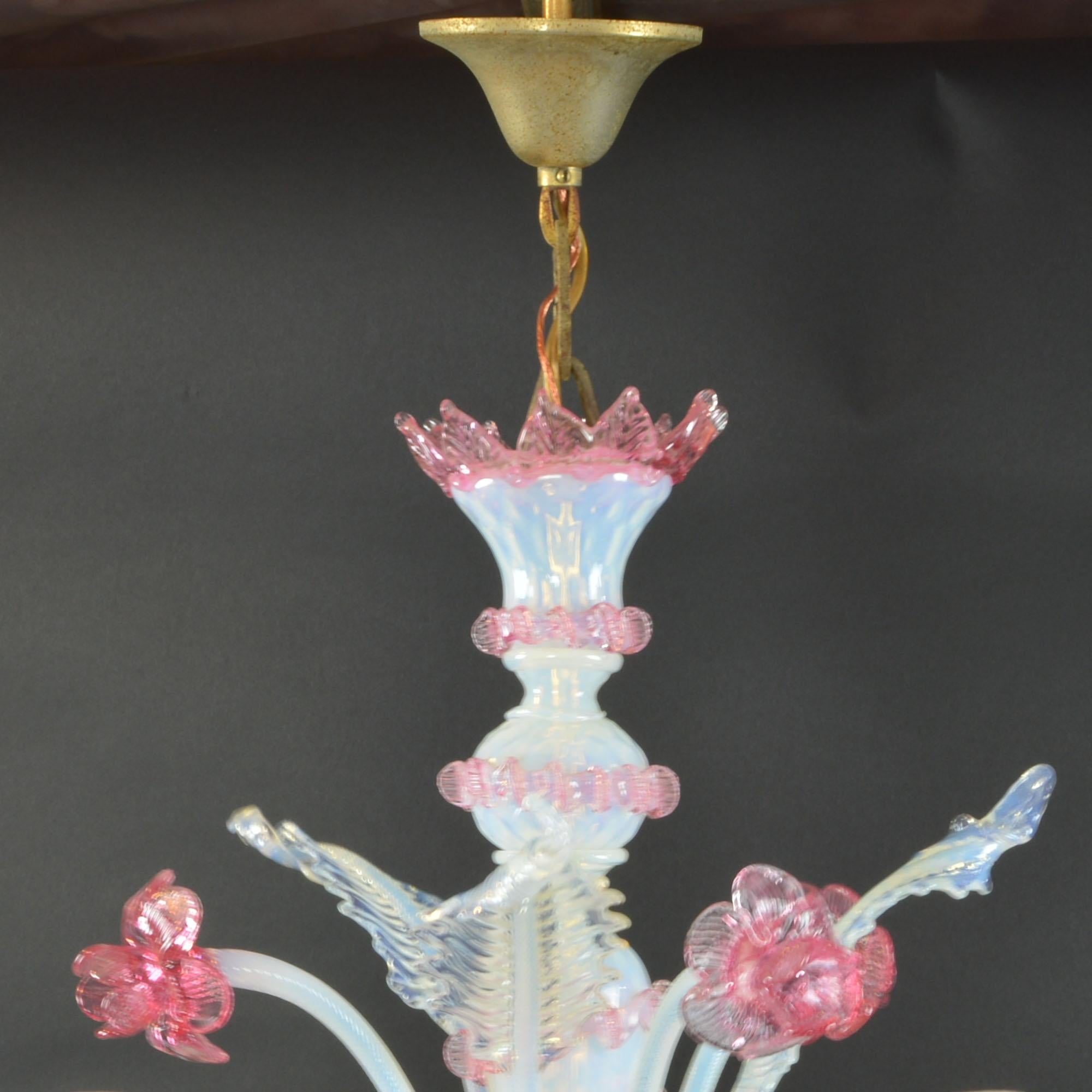 Lovely antique Venetian opalescent glass chandelier in an intriguing white with lovely pink accent color. Venetian glass chandelier has several handcrafted large daffodils and six candle style lights. The lights are mounted on six softly scrolled